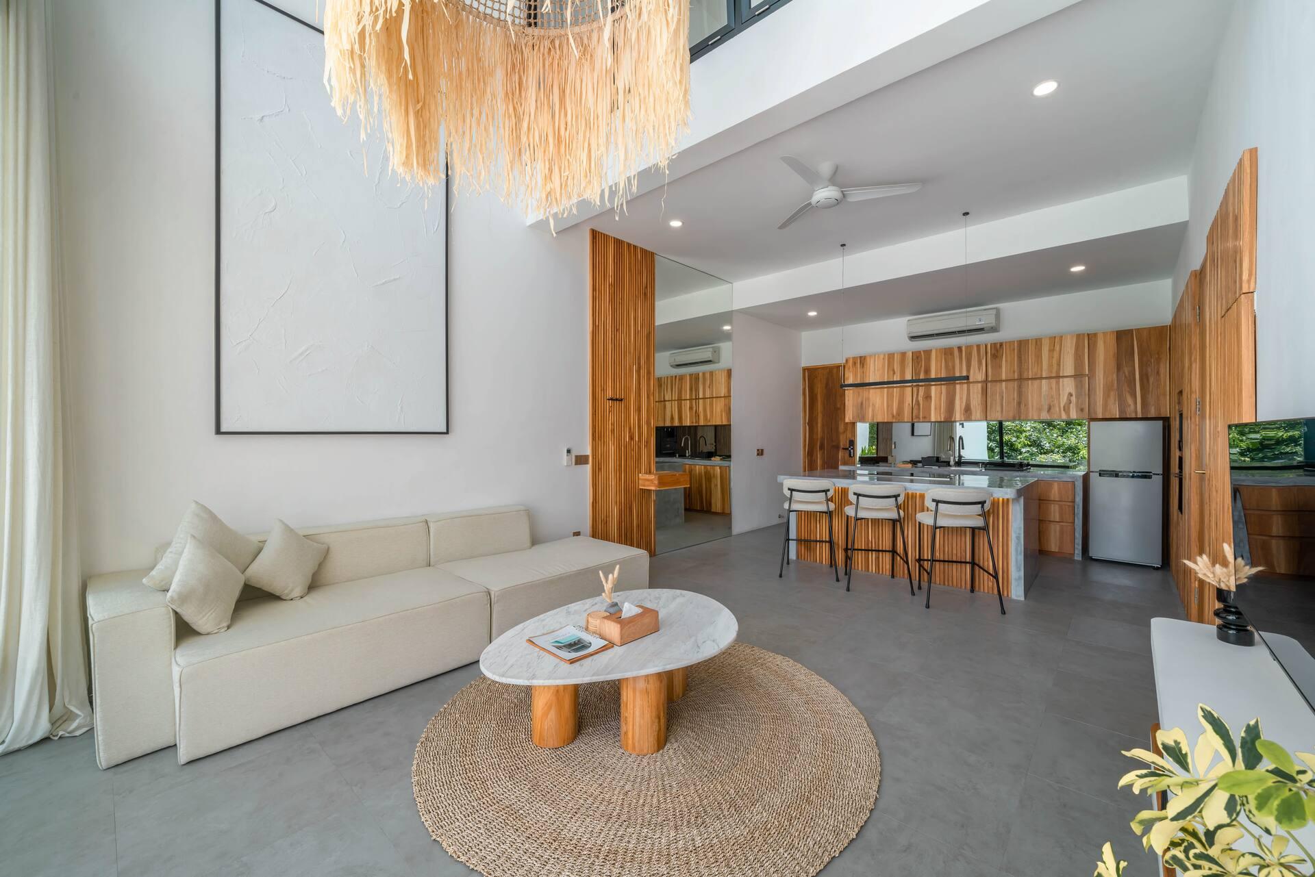 Double-height living room with a white modular sofa, jute rug and the timber kitchen beyond