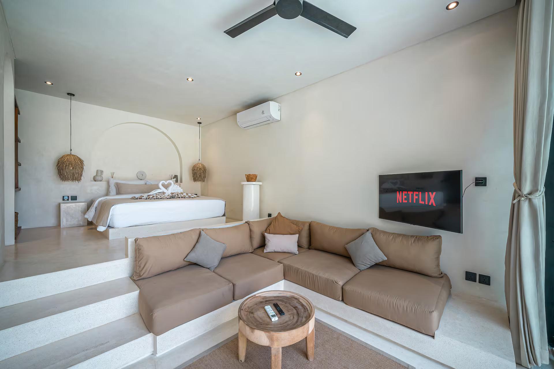 The open room at Villa Lumma 3: a taupe sectional in the sunken lounge, the bed raised behind it
