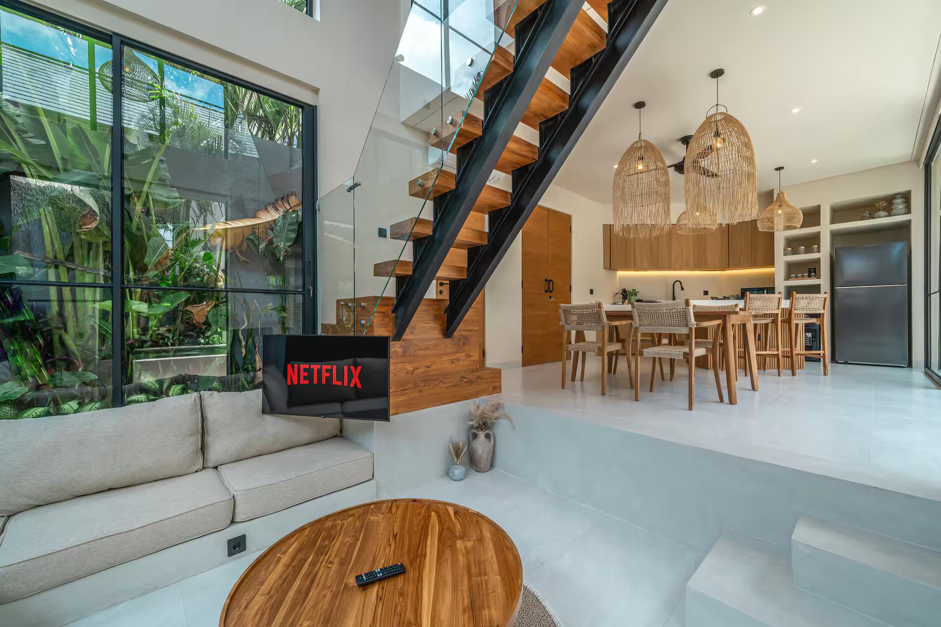 Double-height living room at Villa Yuko with a sunken sofa and an open-tread timber staircase