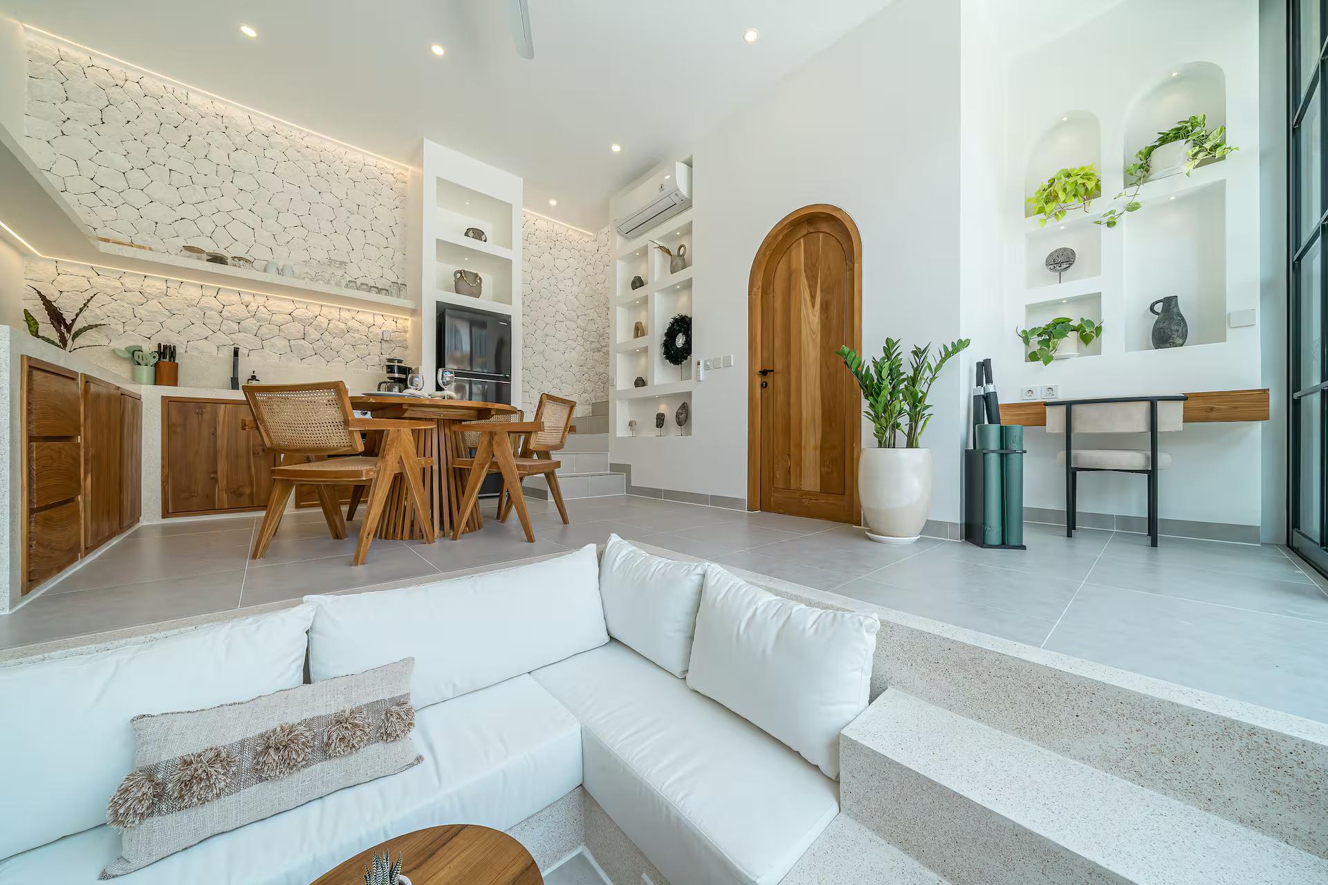 Sunken white sofa built into the floor, steps up to the dining table and kitchen behind