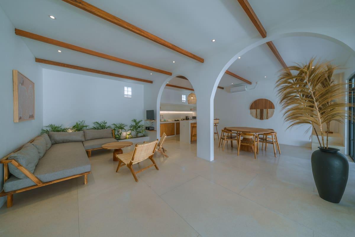 Ground-floor living room at Villa Eliad, an L-shaped timber sofa beneath exposed beams