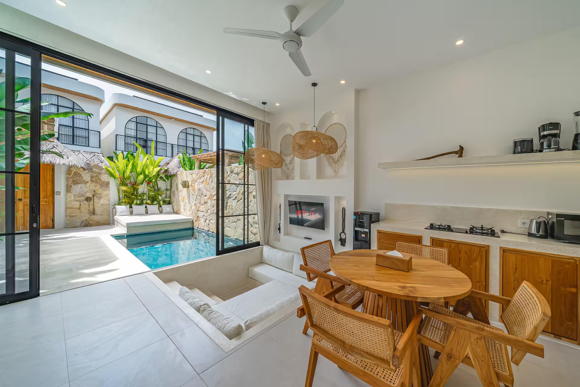 Living and dining opening to the pool through full-height black-framed glass