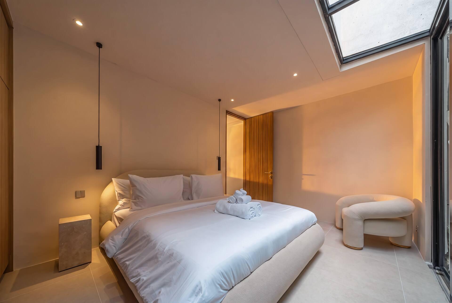 Ground-floor bedroom at Enso 4, its skylit ceiling washing daylight down the plaster walls