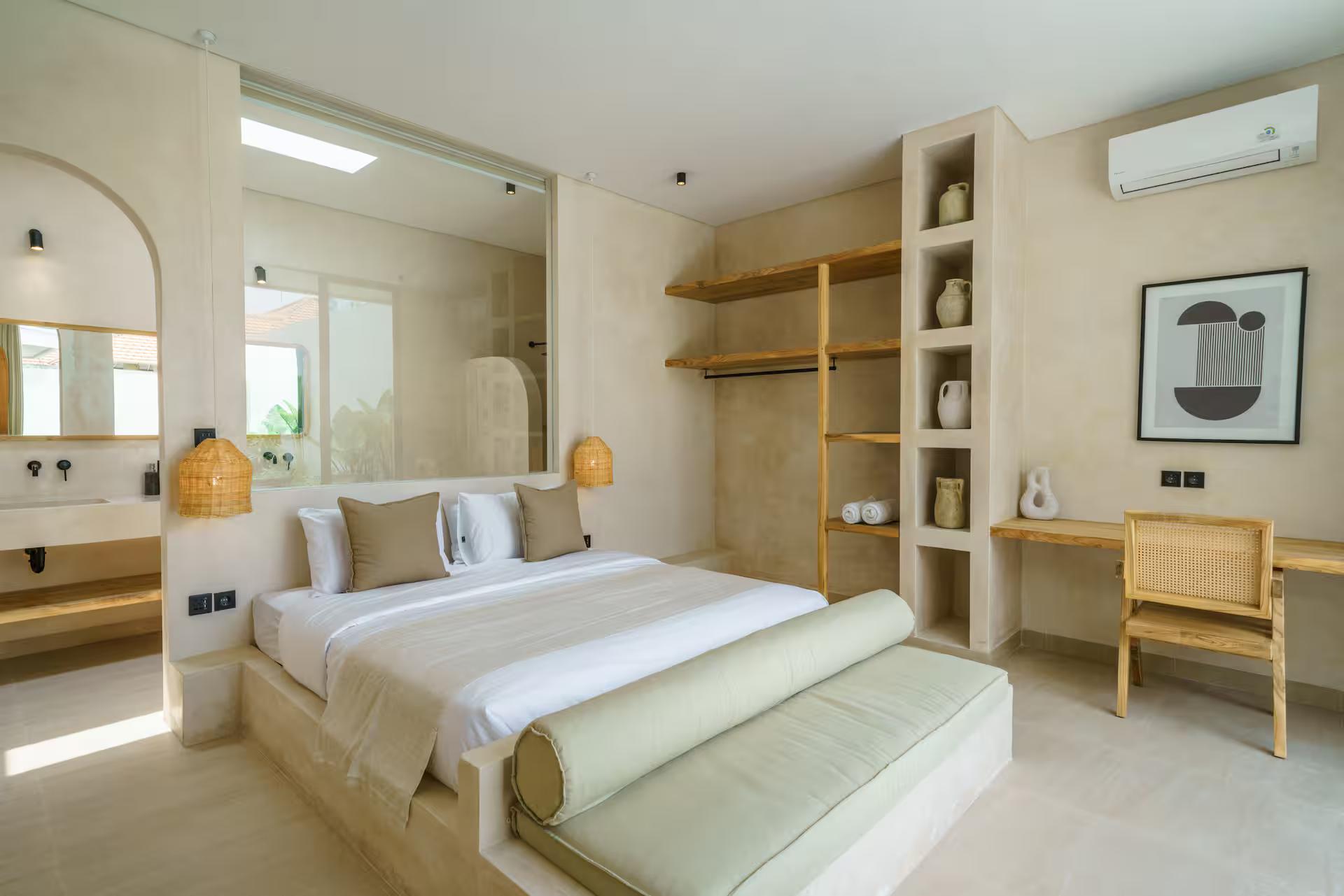 King bedroom at Villa Leros with built-in timber shelving, a cane desk chair and an arched mirror
