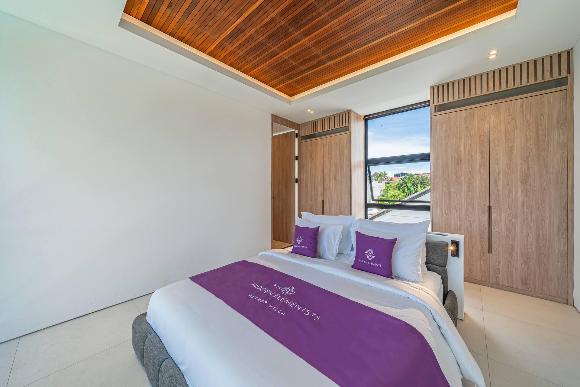 King bedroom under a timber-slatted coffered ceiling, with purple Hidden Elements linen and cove lighting