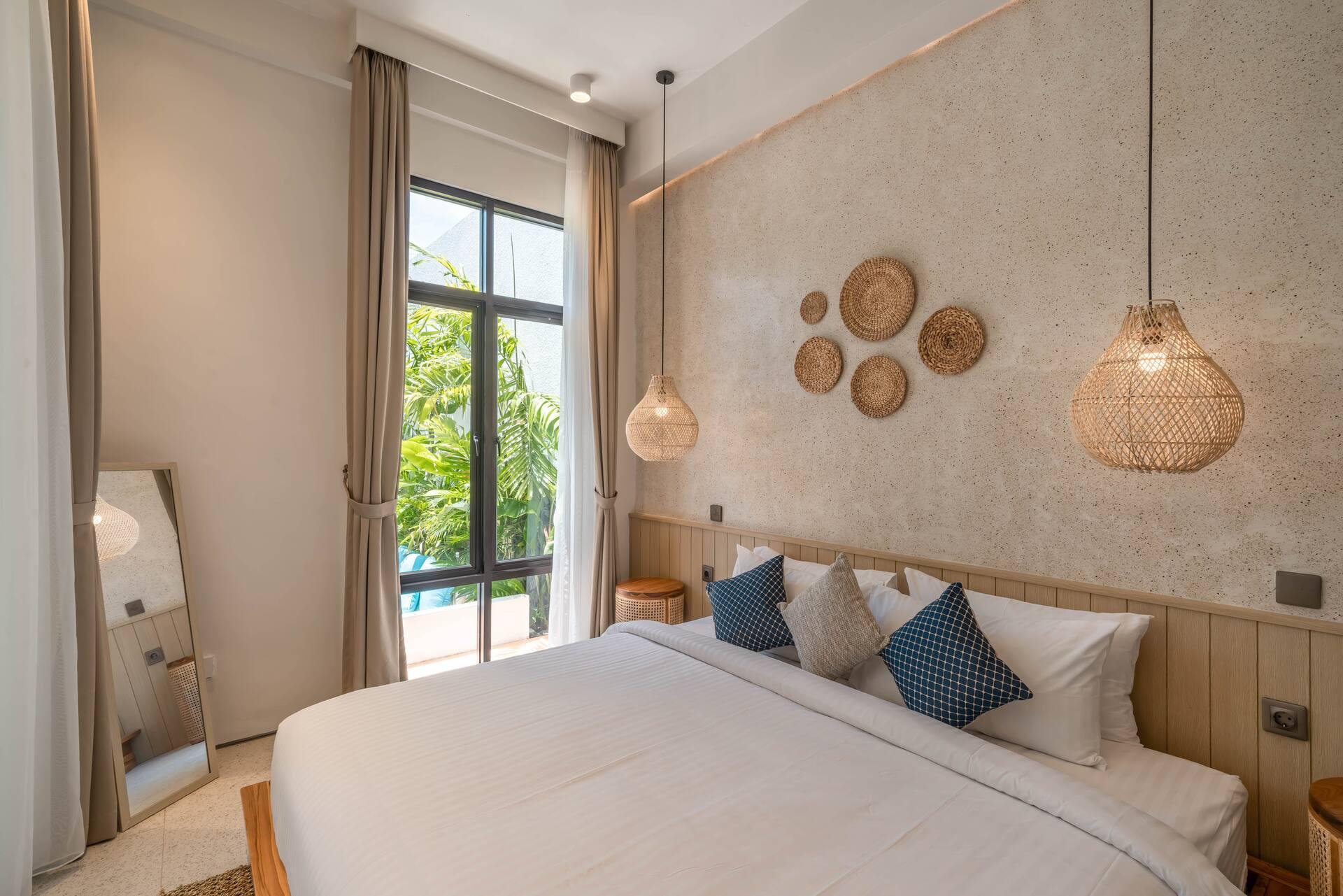 The upper bedroom, with woven rattan discs on a limewashed headboard wall and indigo cushions