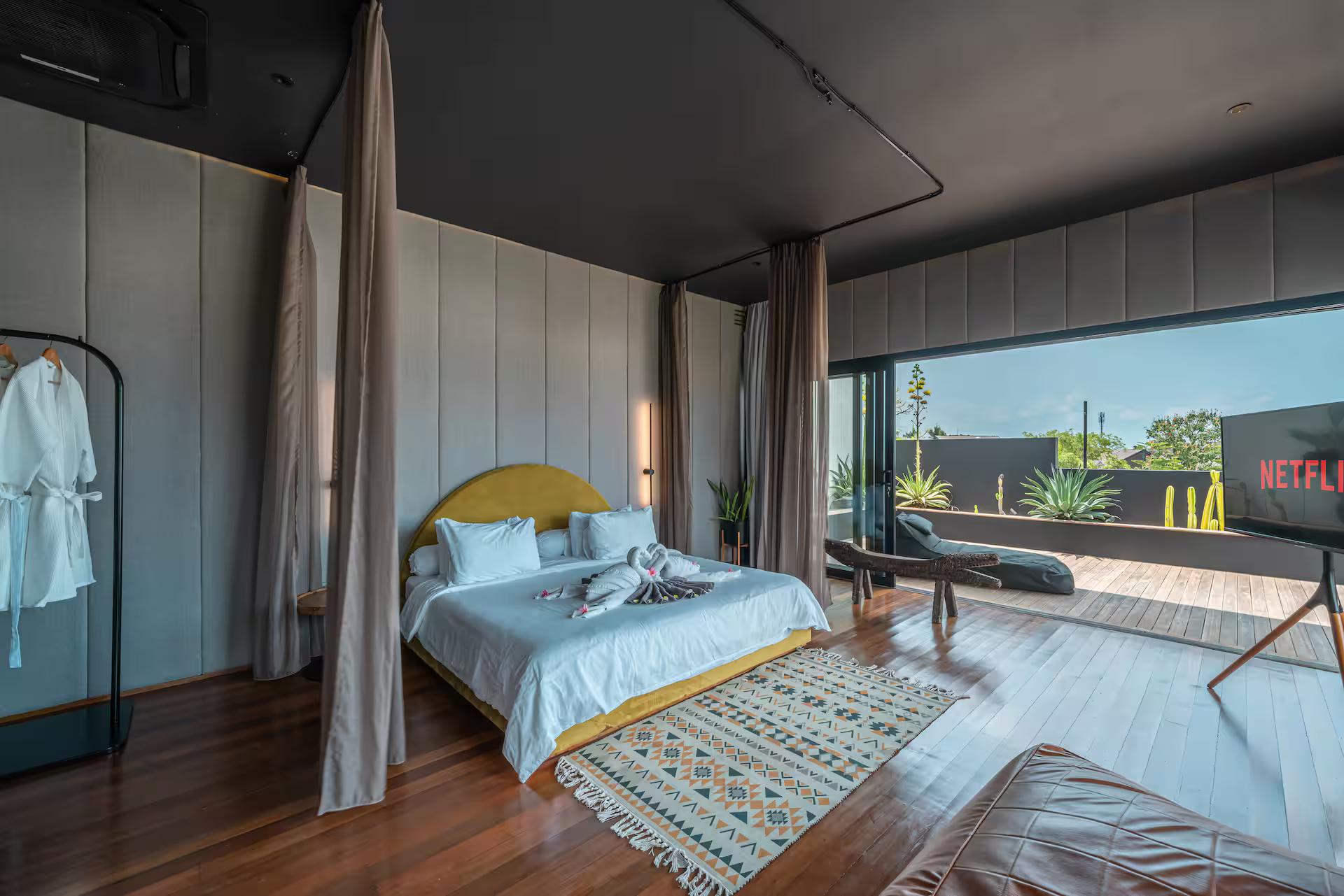 Timber-lined master bedroom at Villa Sunset Berawa, doors open to its own deck