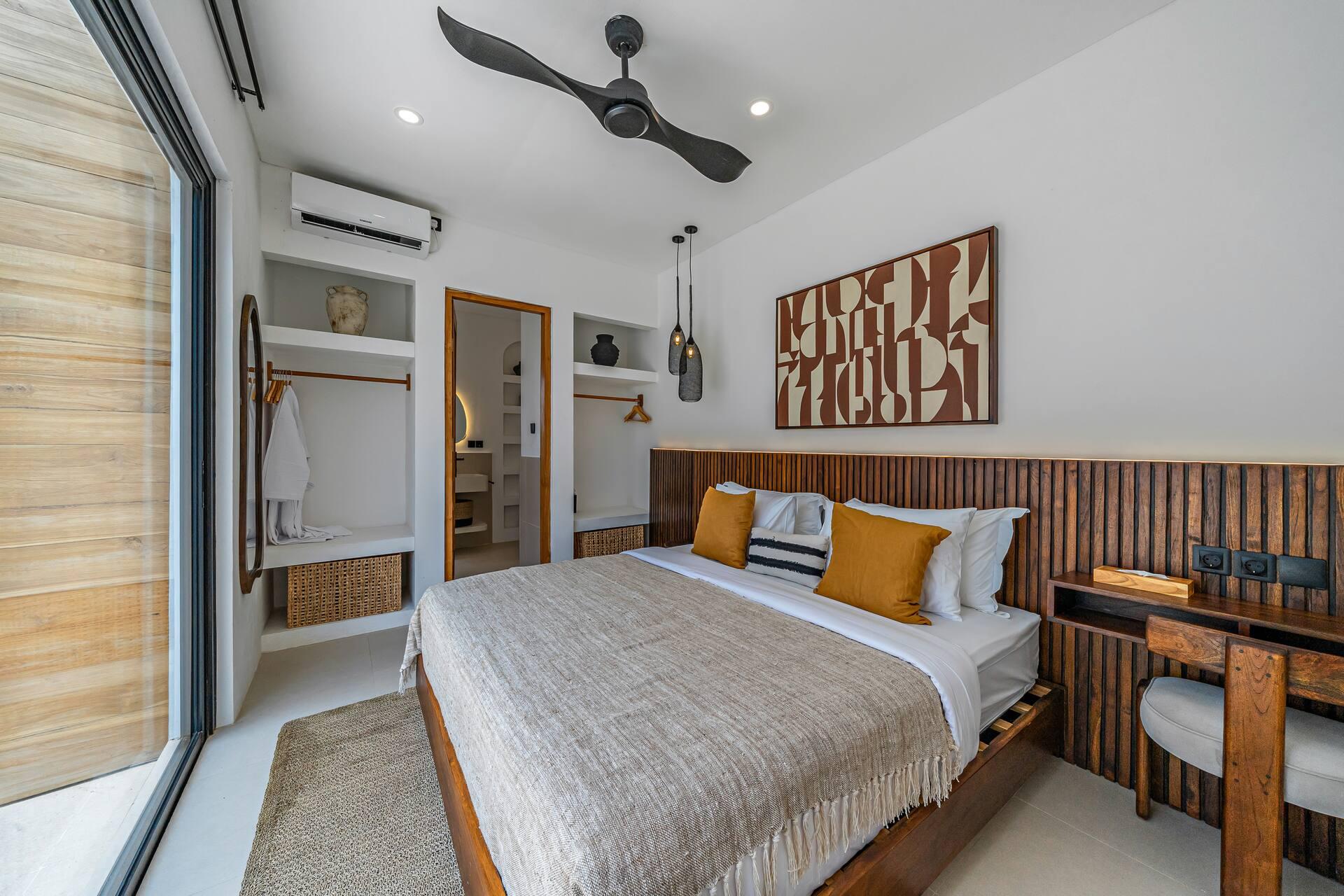 Bedroom with a fluted timber headboard, ochre throw and a mirrored wardrobe alcove