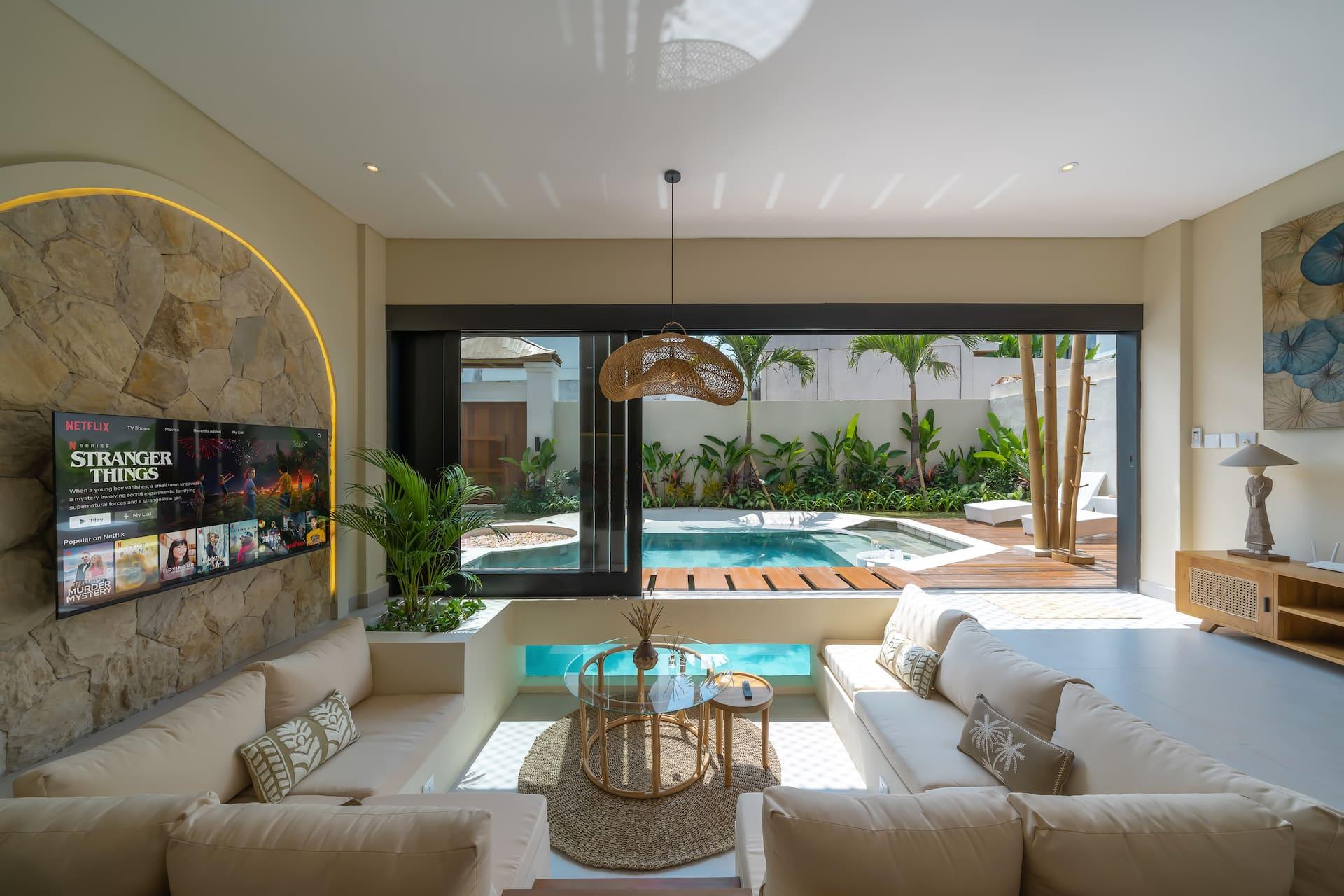 Cream L-shaped sofa in the step-down lounge, television set into a rough stone arch