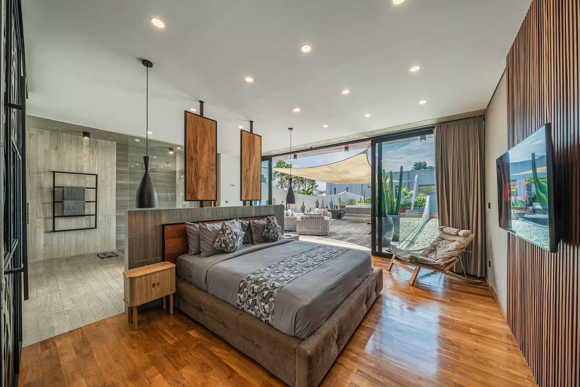 King bedroom at Villa Aless with a timber floor and glazing onto the pool terrace