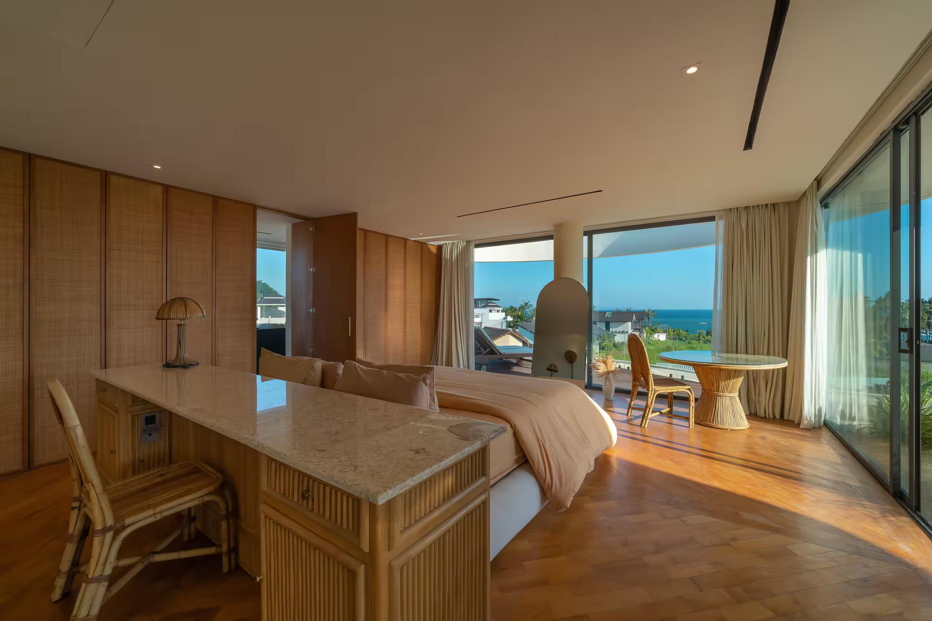 King suite with a rattan writing console and full-height glass onto the rice fields and sea