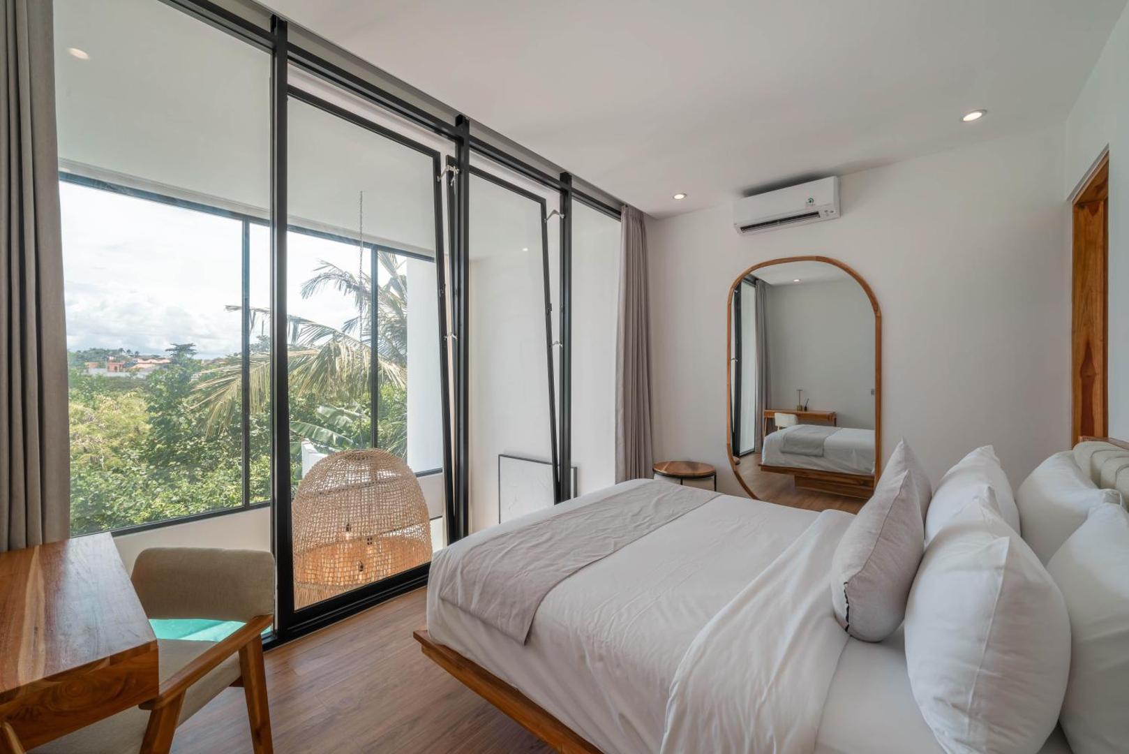 Upstairs bedroom at Villa Finity A, arched mirror and a glass wall open above the pool