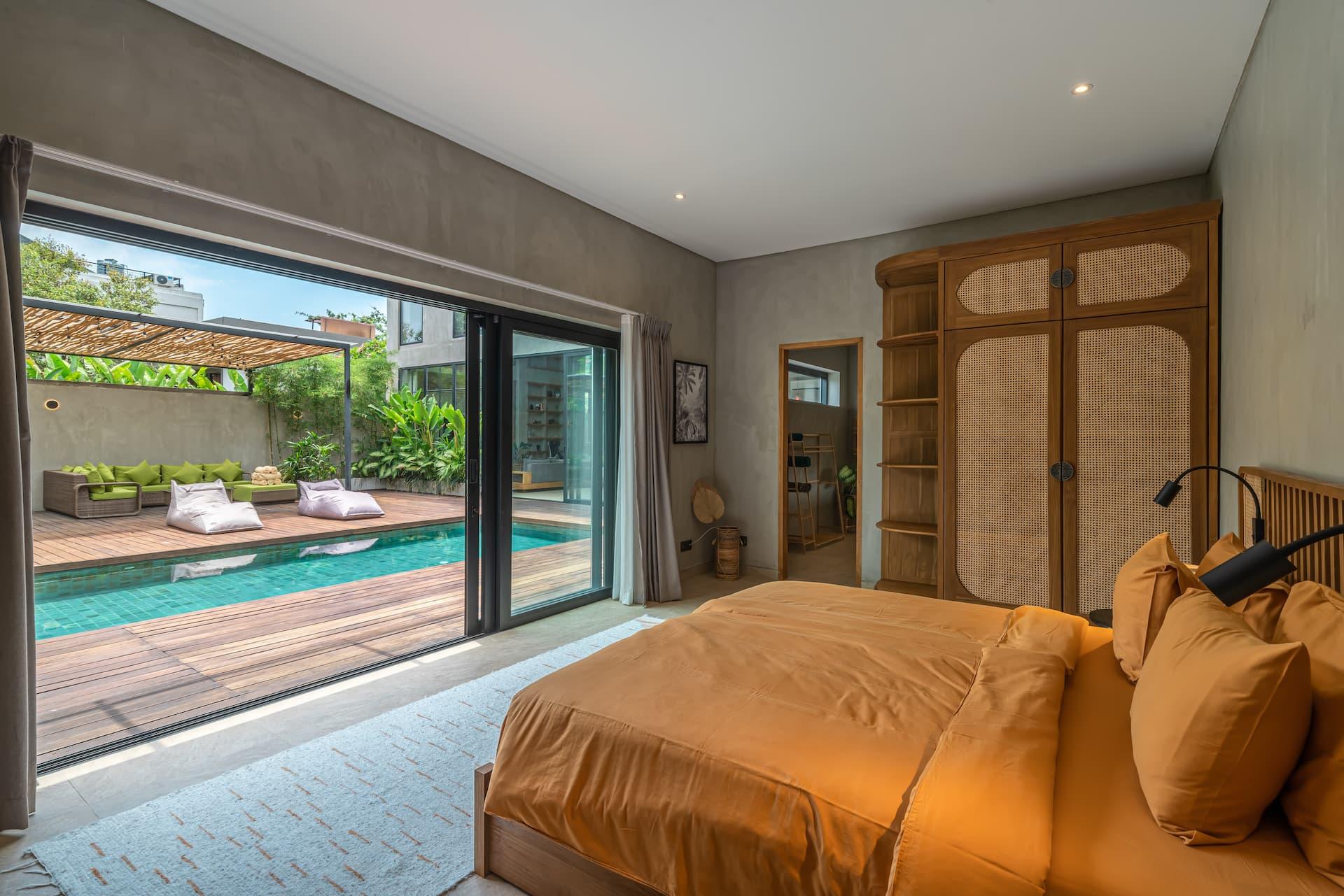 Villa Zenloft bedroom whose sliding glass wall opens straight onto the pool deck