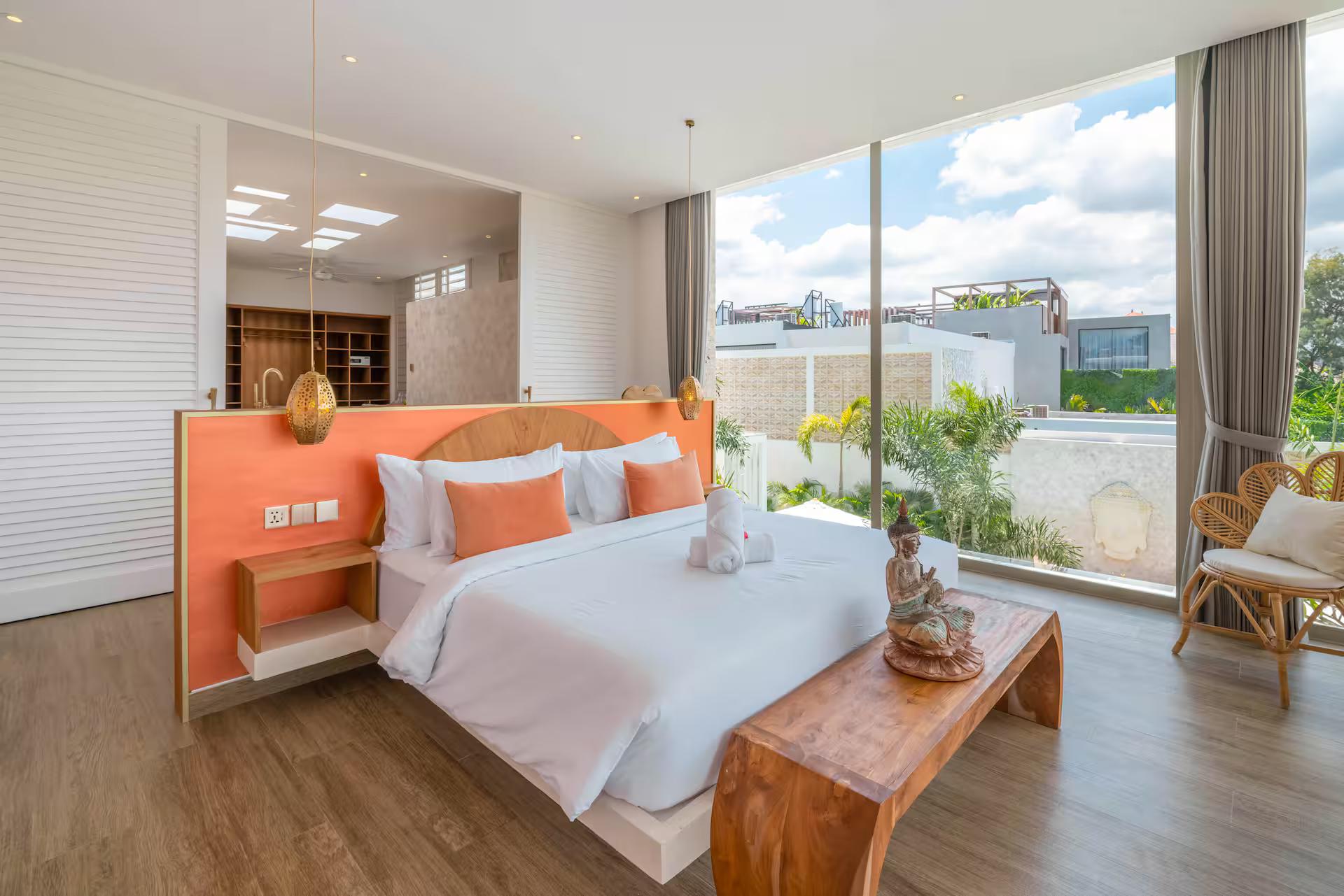 Master bedroom with an orange upholstered headboard and glass sliding straight to the pool