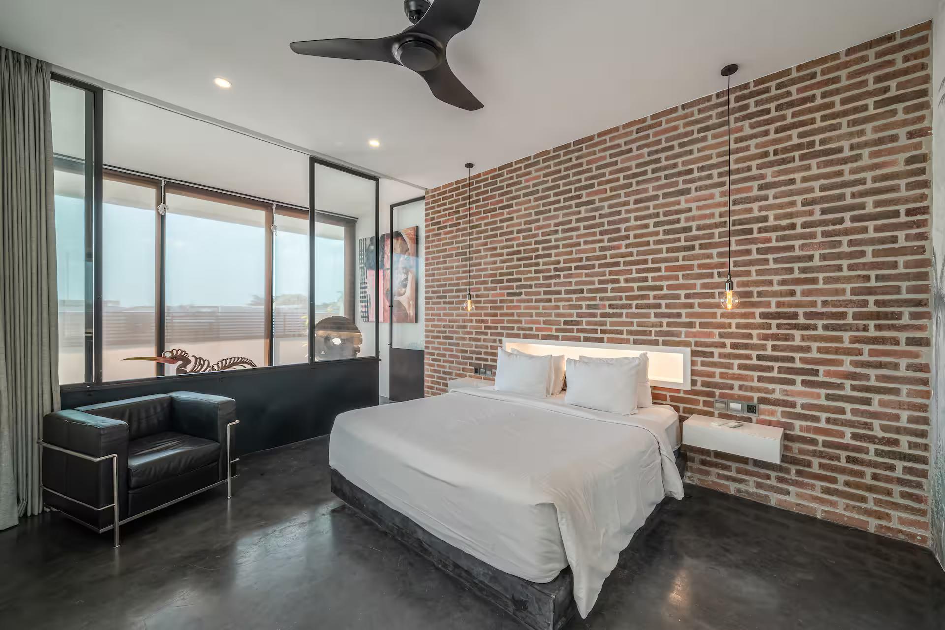 King bedroom at Loft Ludo 3 with an exposed red-brick wall and a leather armchair