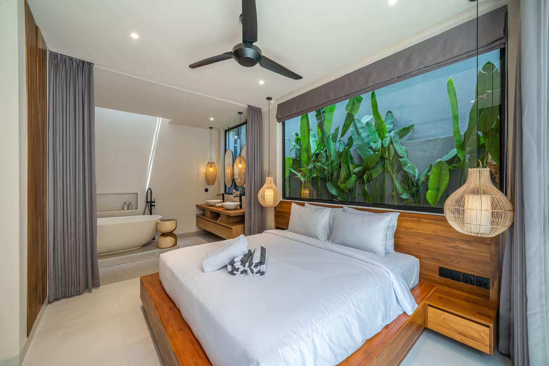 King bedroom with a timber-slab headboard and a window filled with banana and heliconia leaves