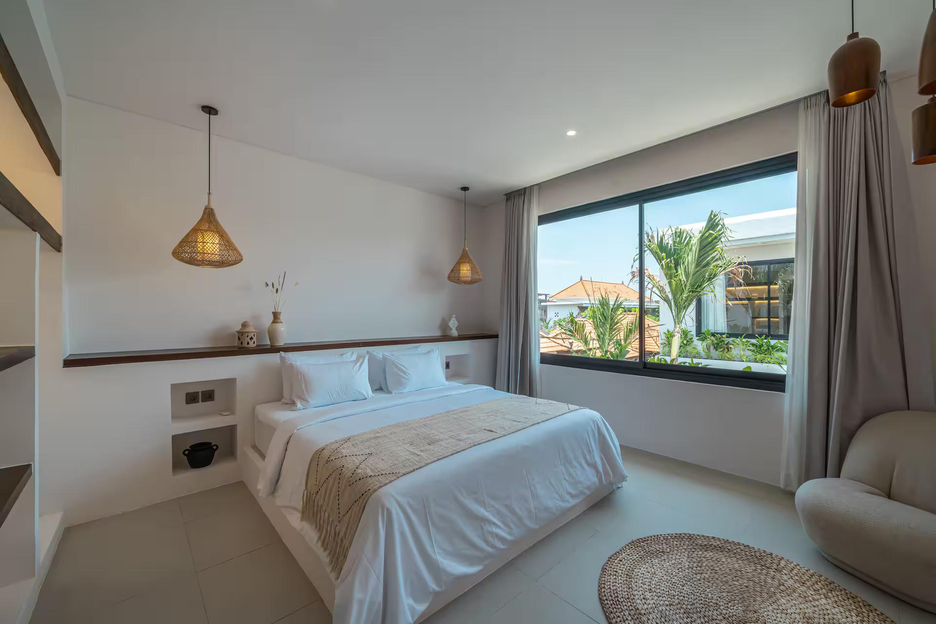 Upstairs bedroom with a king bed under a wide window and twin rattan pendants