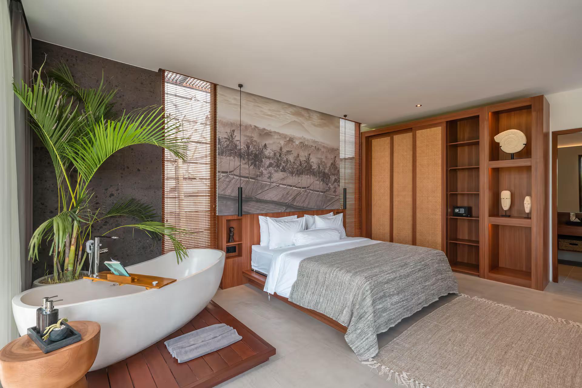 Master bedroom with a freestanding oval tub standing in the room beneath a landscape mural