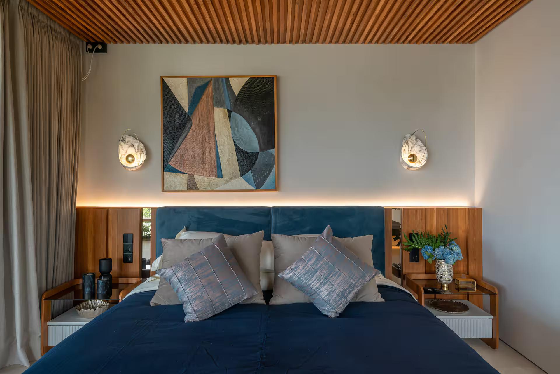 Master bedroom with a navy velvet headboard under a slatted timber ceiling
