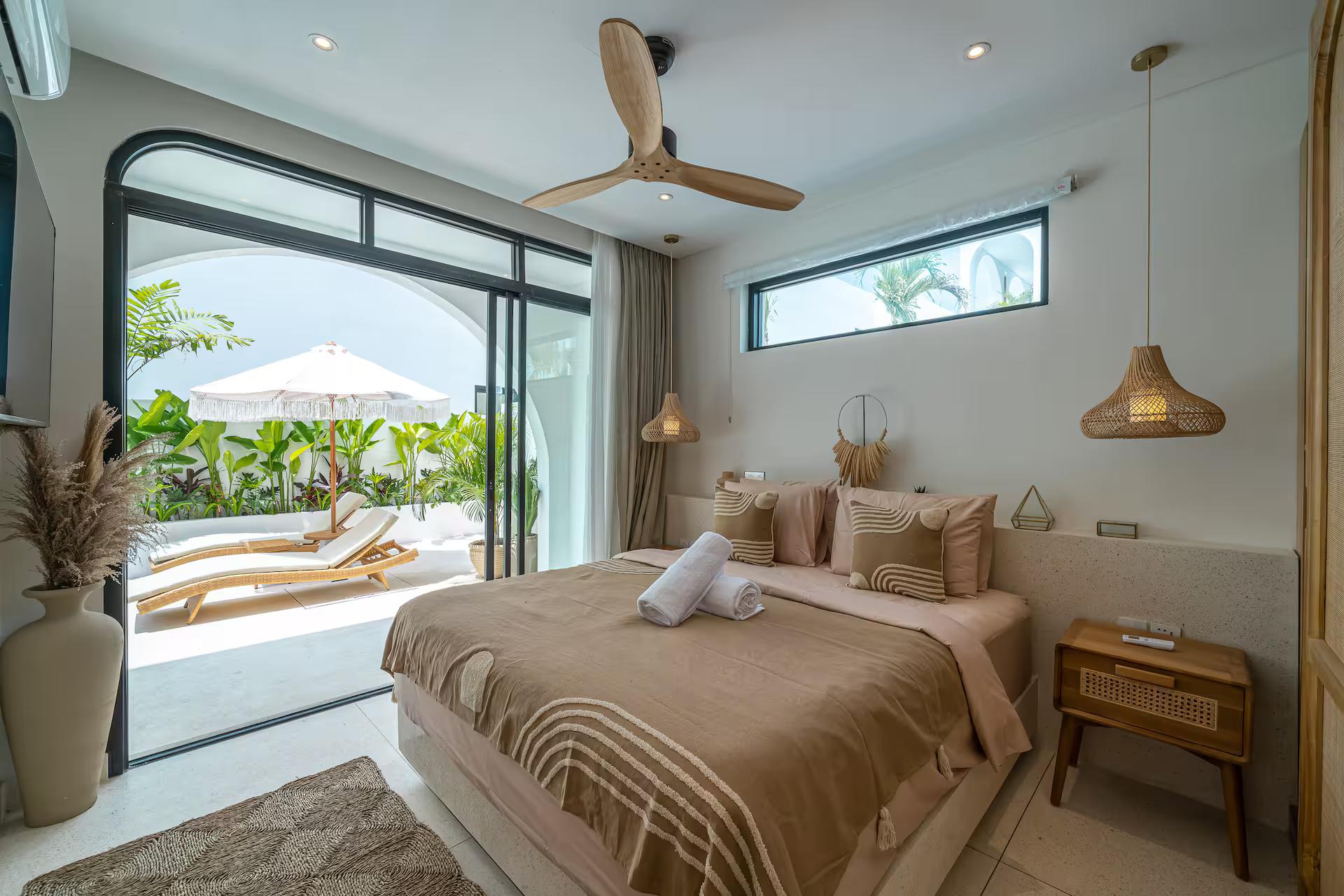 King bedroom with rattan pendants and glass doors opening onto the pool terrace at Casa Amici 8