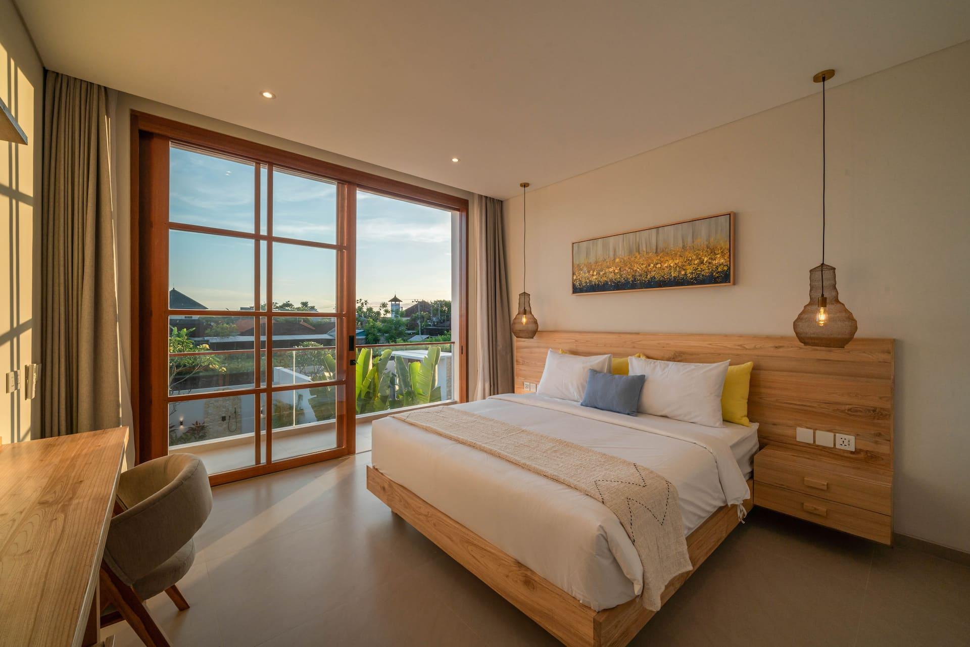 Master bedroom at Villa LouLou with a king bed, timber headboard and full-height windows onto the garden