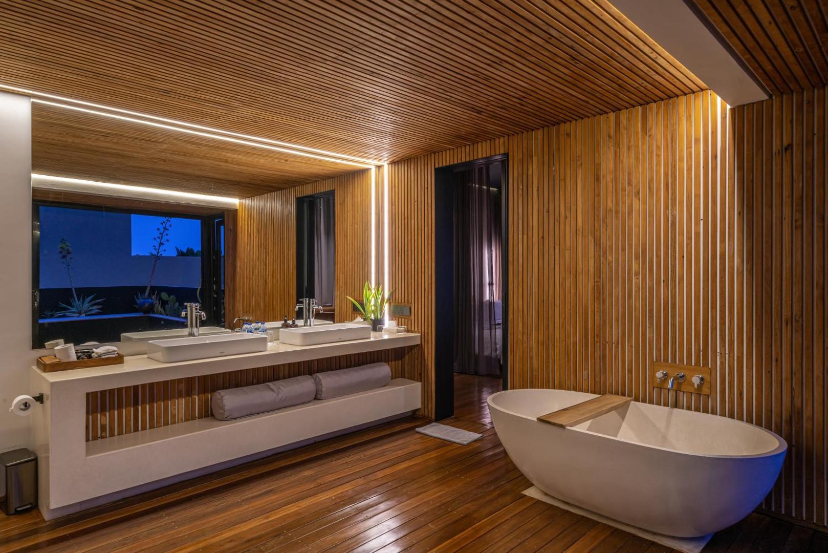 Freestanding stone bath beside a long timber vanity in the third-floor suite