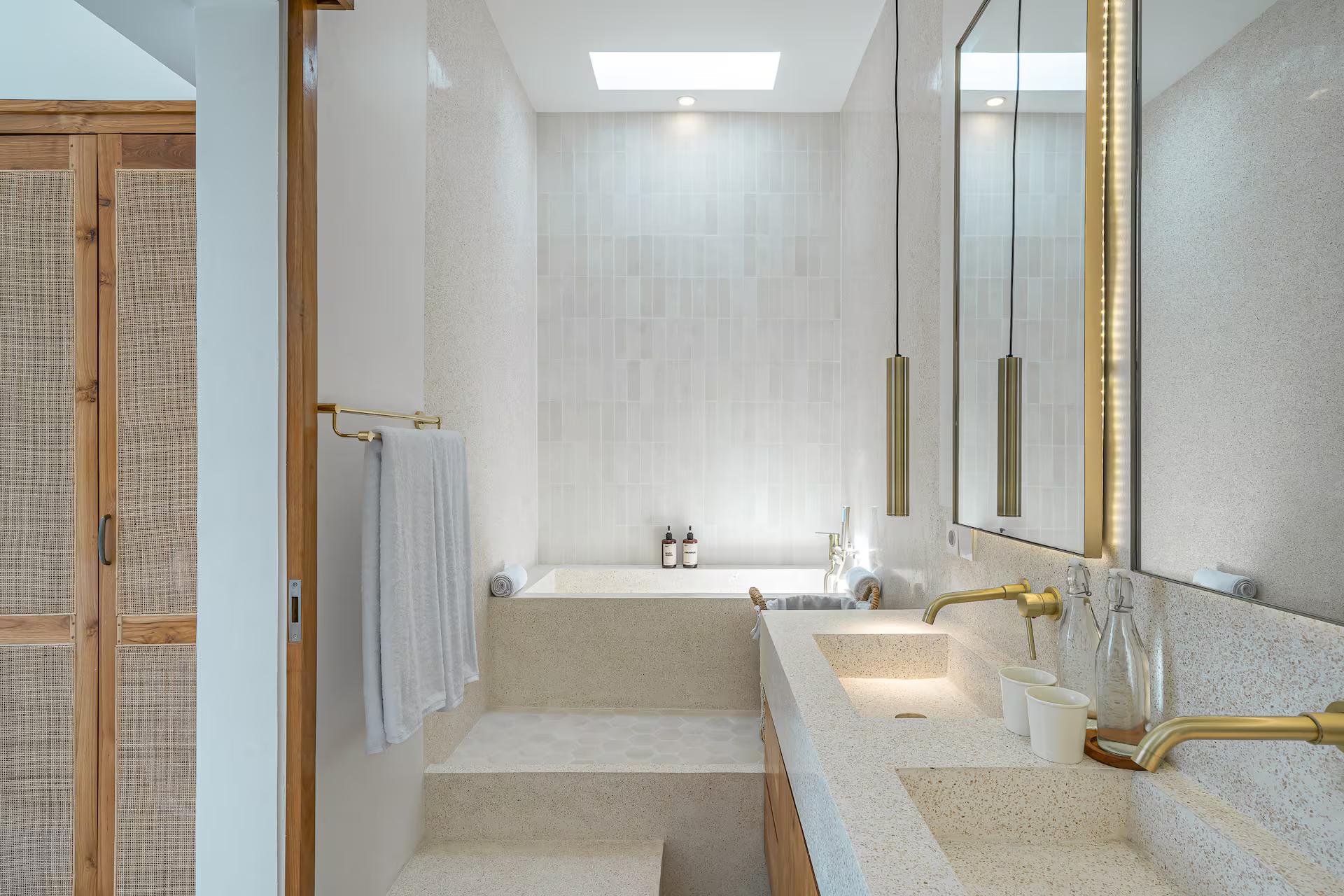 Deep bath set into terrazzo under a skylight with brass tapware in the Mareo en-suite