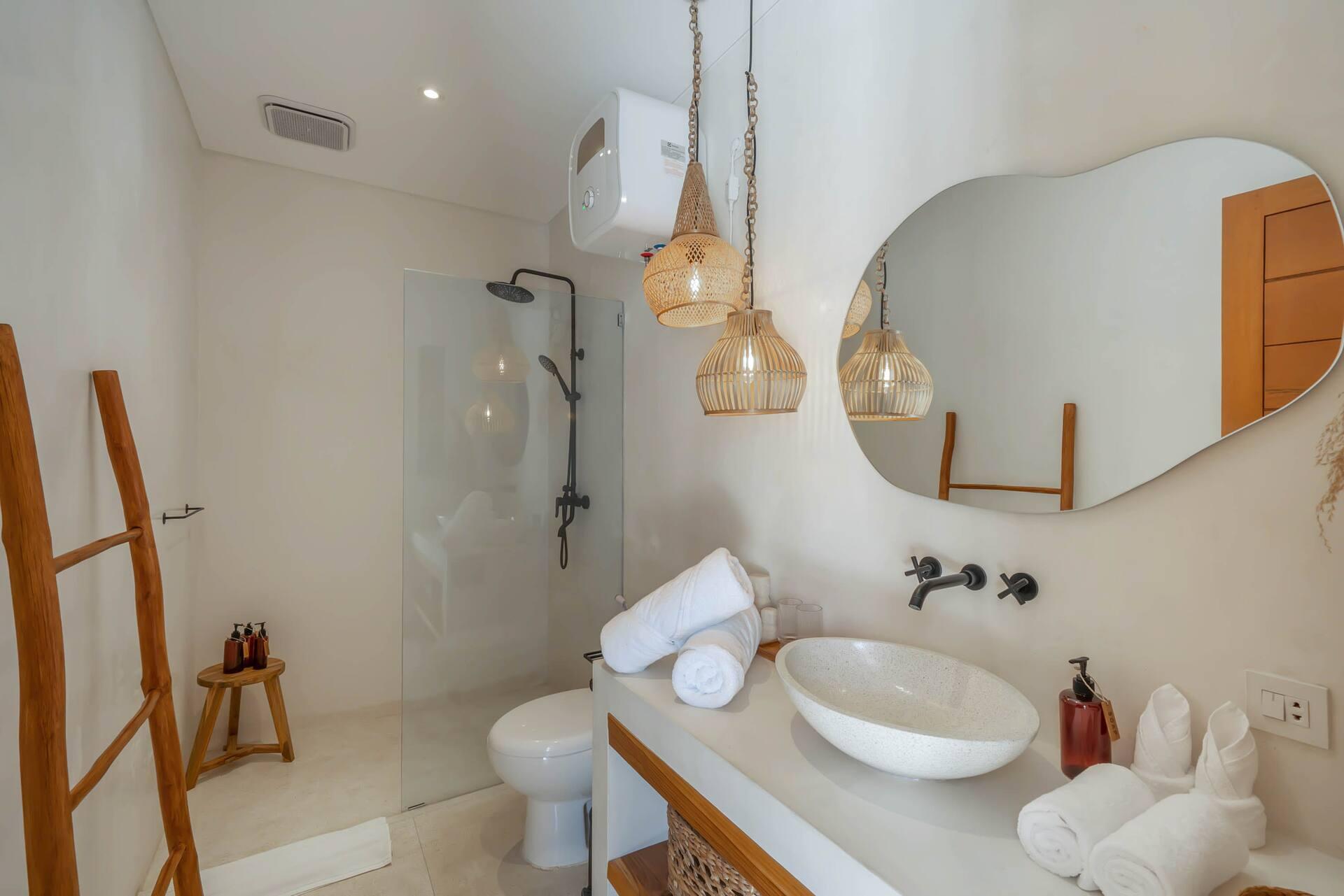 Bathroom with an organic-shaped mirror, stone basin and a timber ladder rail at Villa Heiwa