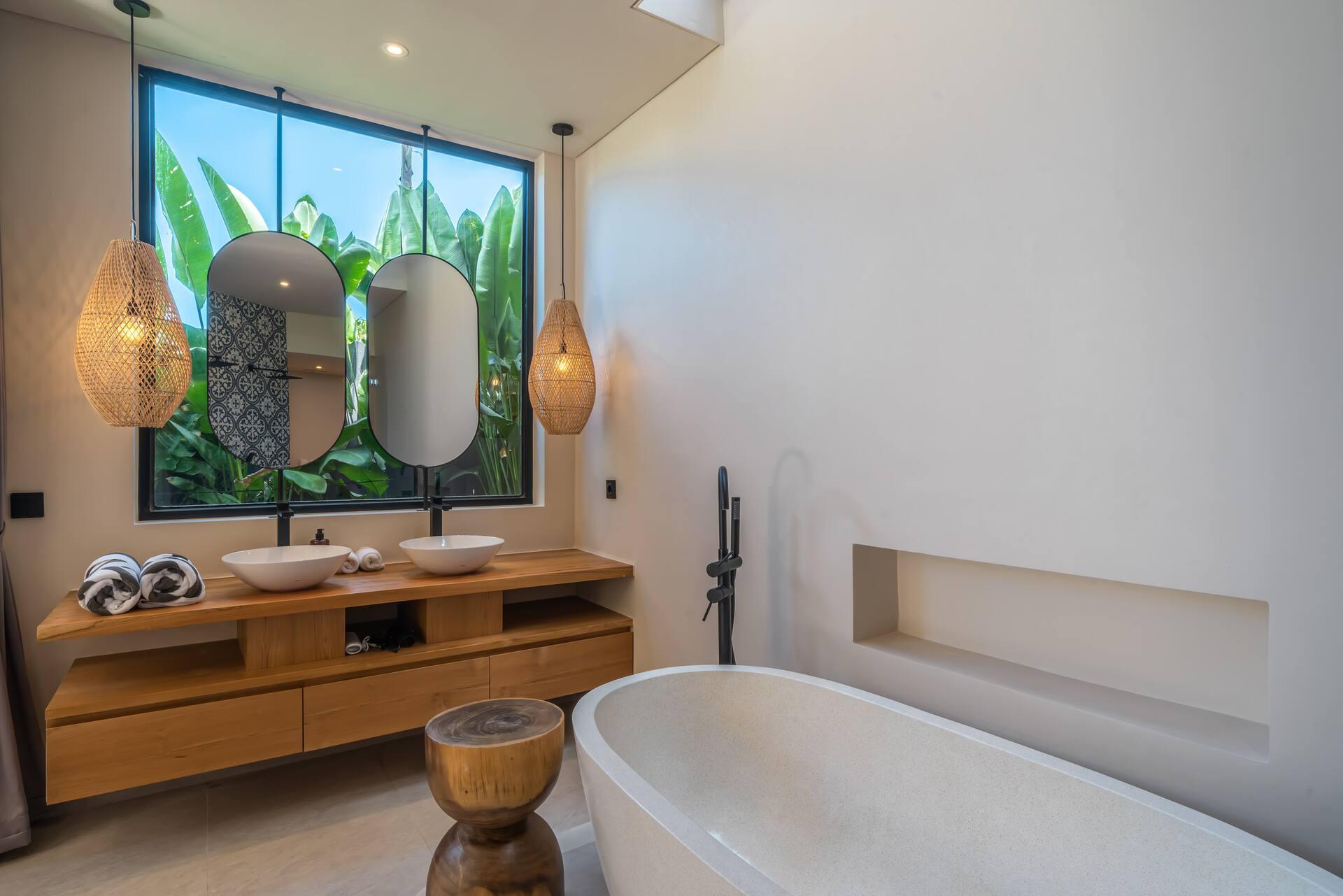 Freestanding stone tub and a timber vanity with two oval mirrors in the en-suite