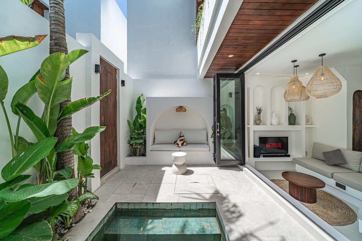 Arched daybed alcove built into the courtyard wall beside the pool, banana palms overhead