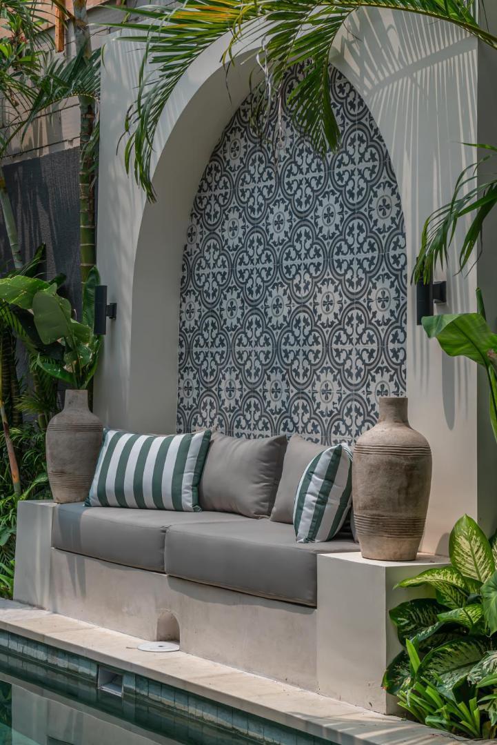 Tiled arch above a built-in stone bench beside the pool, terracotta urns either side
