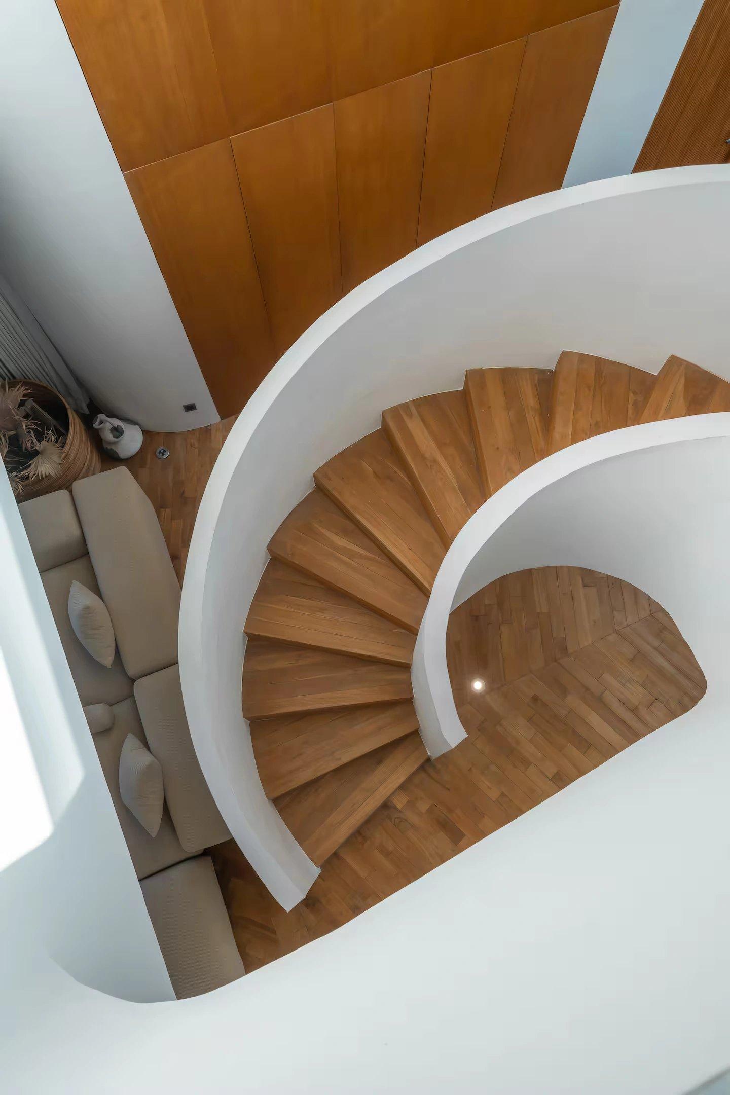 Solid timber treads winding inside the white plaster drum of Villa Babylon's spiral stair