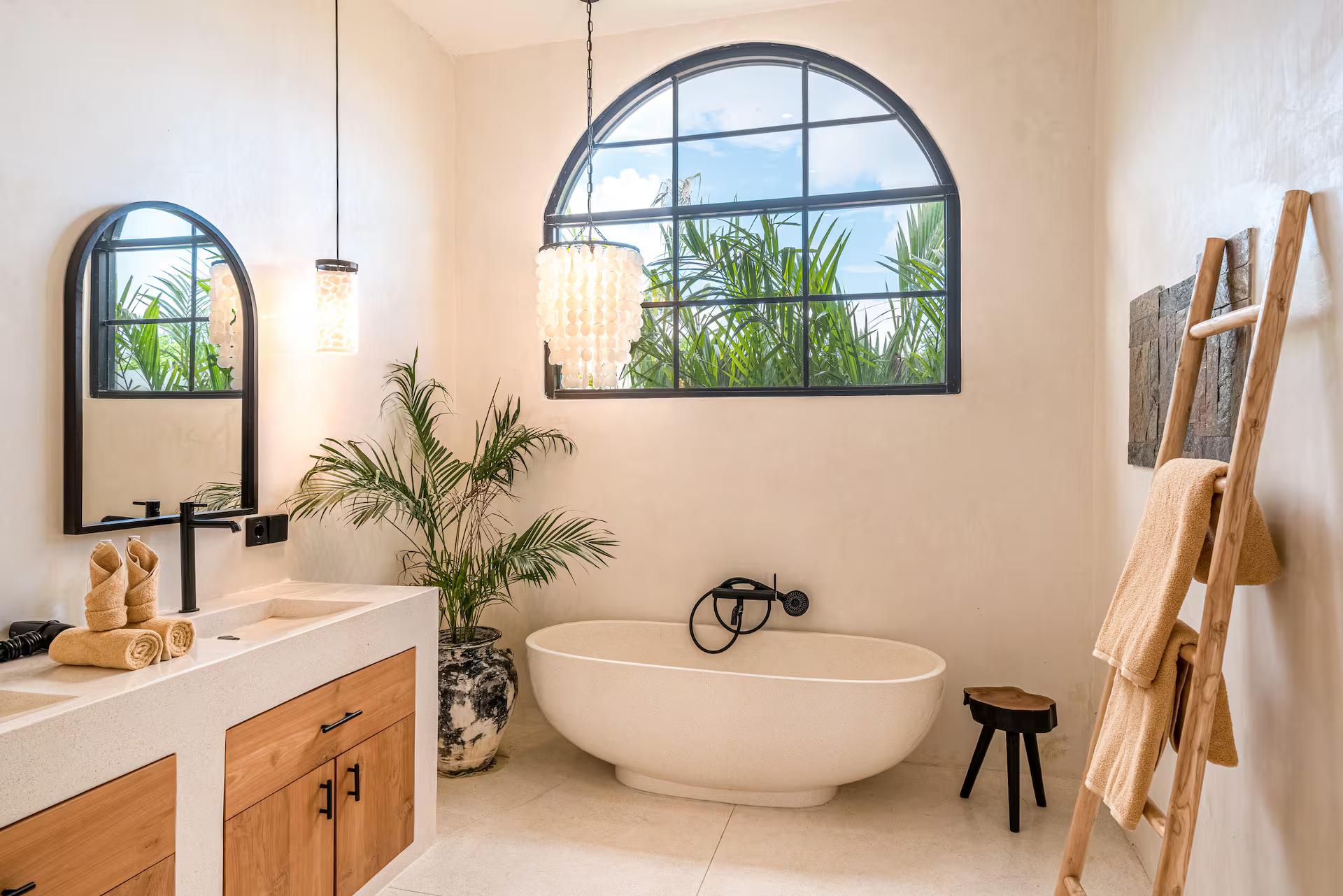 Freestanding stone tub below the arched window in the en-suite at the macan Bingin