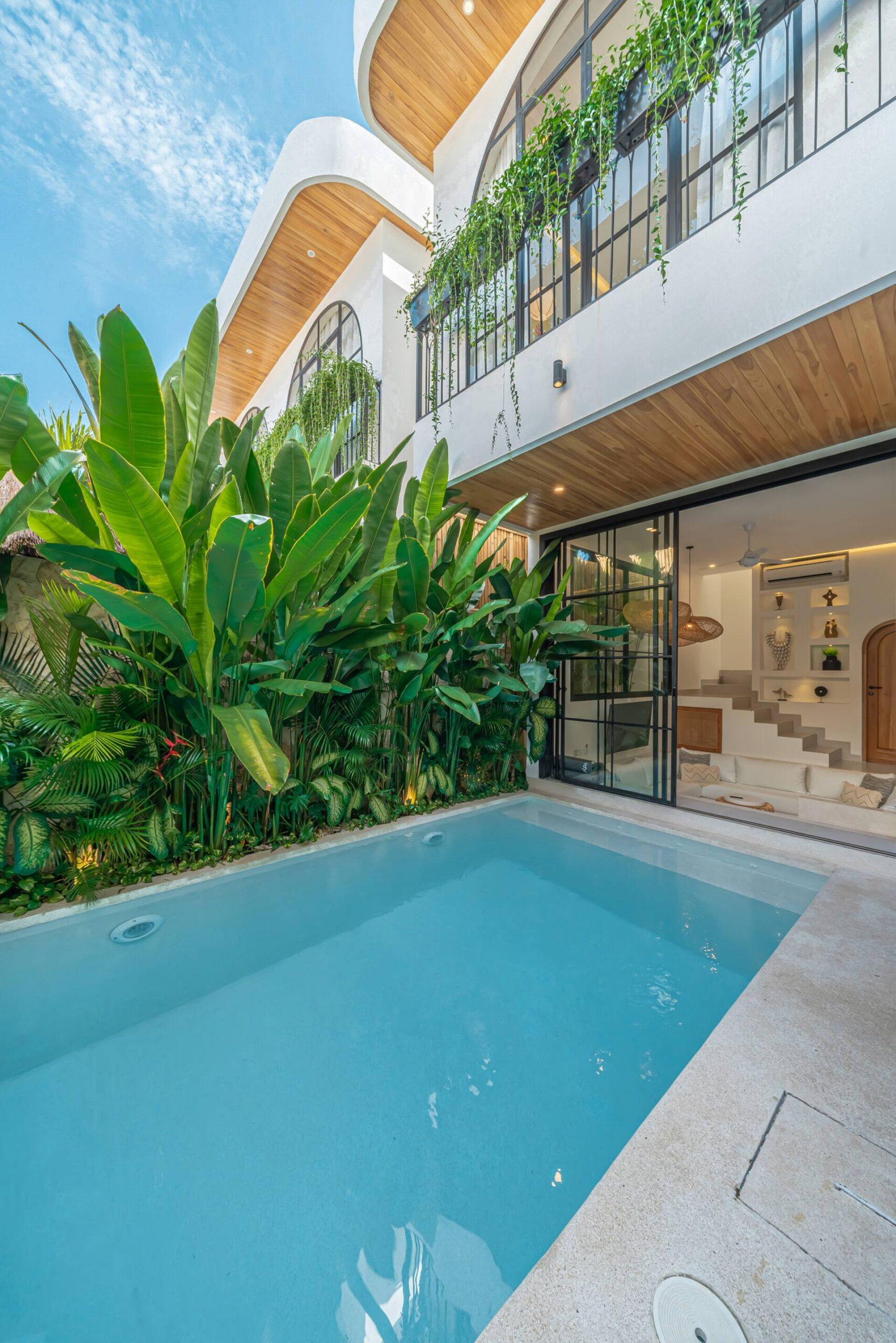 Two-storey white facade of Villa Sagu above the pool, framed by banana palms