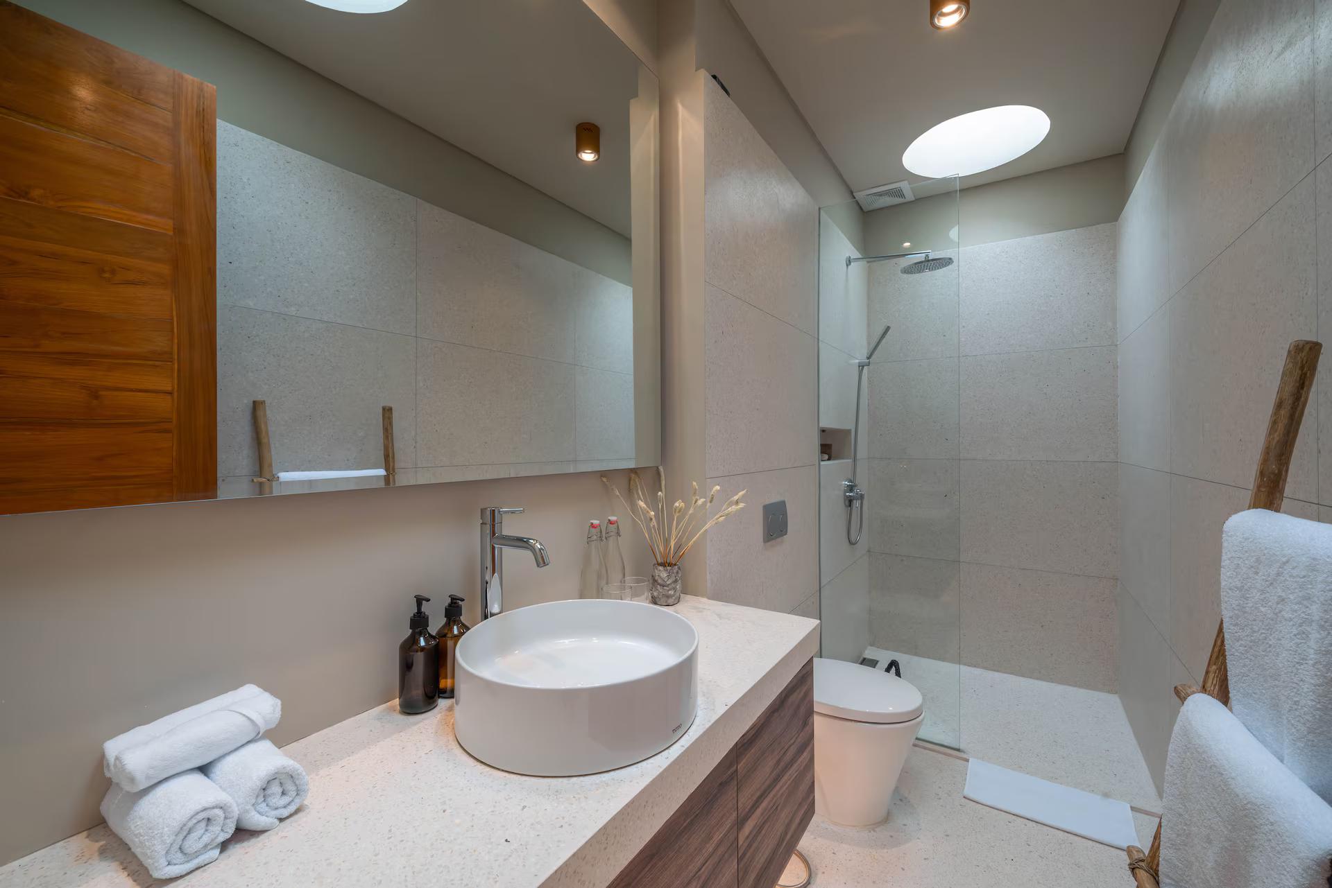 Bathroom with a round stone basin on a timber vanity and a glass walk-in shower
