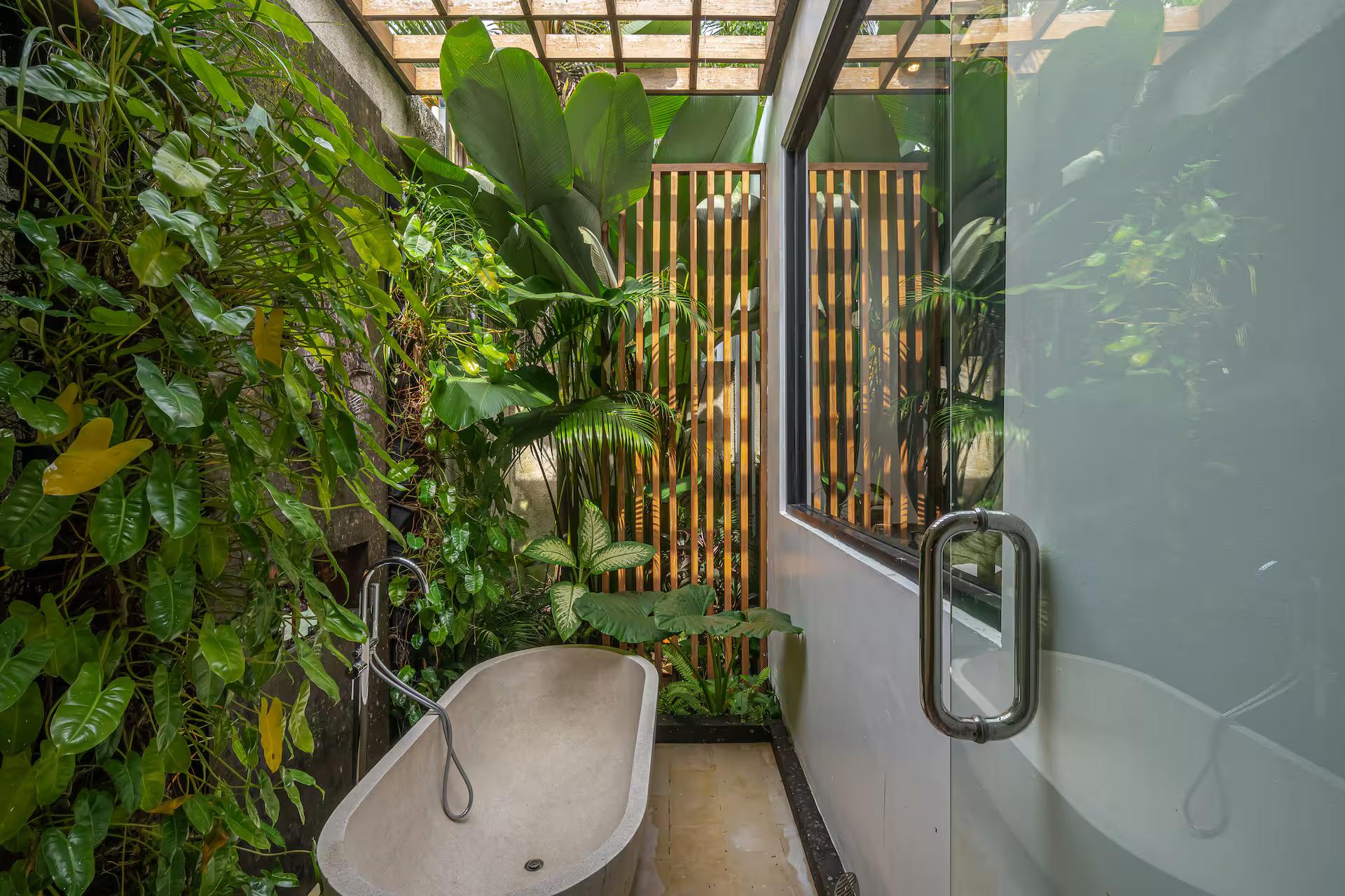 Stone bathtub set against a living wall of foliage in the garden bathroom at Villa Yuka