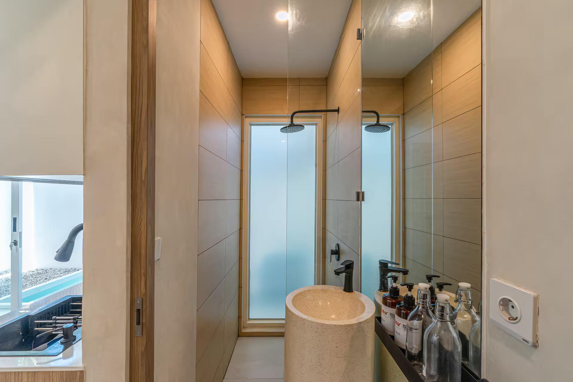 Timber-lined bathroom with a walk-in rain shower and a round drum basin in pale stone