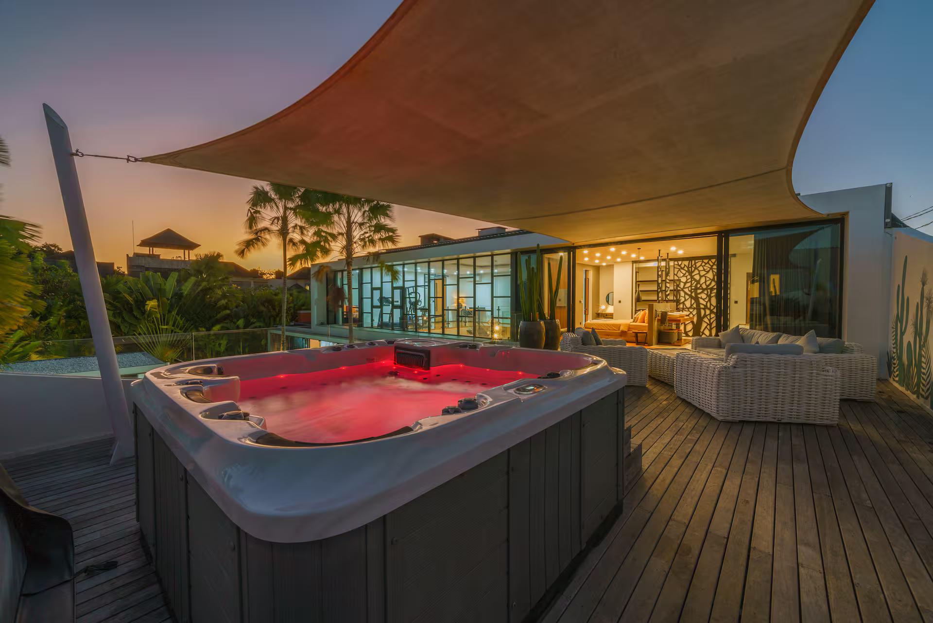 Rooftop jacuzzi lit at sunset on the timber deck at Villa Aless, shade sail overhead