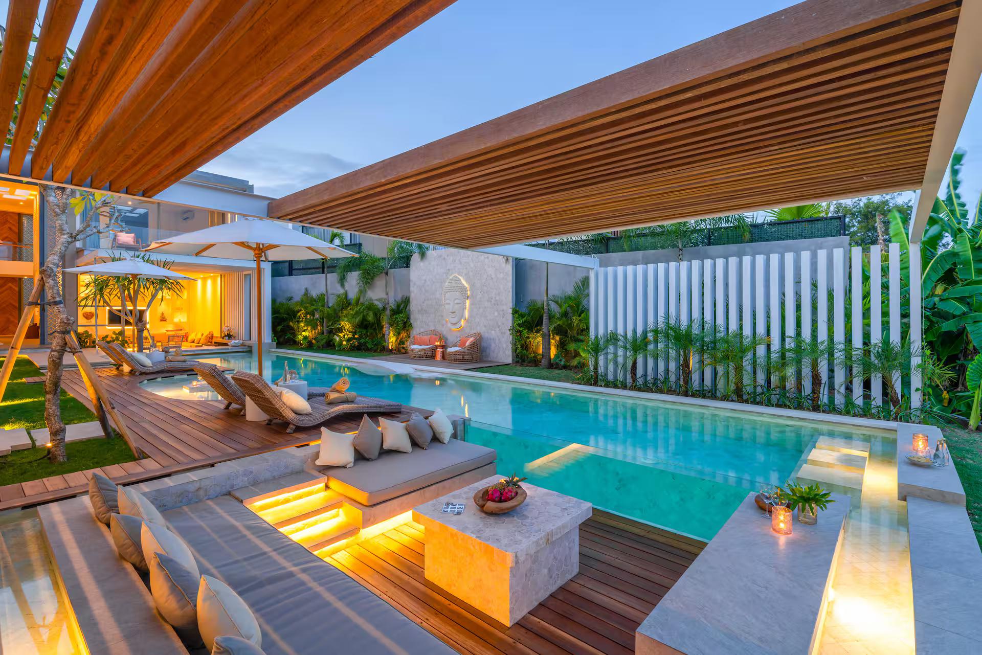 Sunken sofa group beside the pool at Villa Vida & Vola, lit under its timber canopy