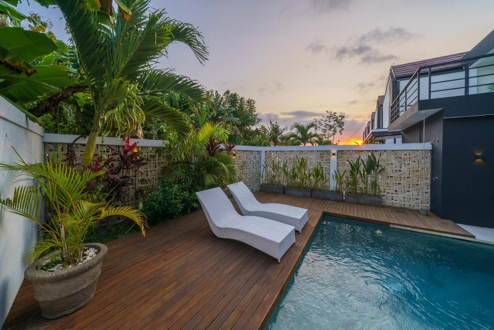 Sun loungers on the pool deck at dusk, palms silhouetted against the evening sky