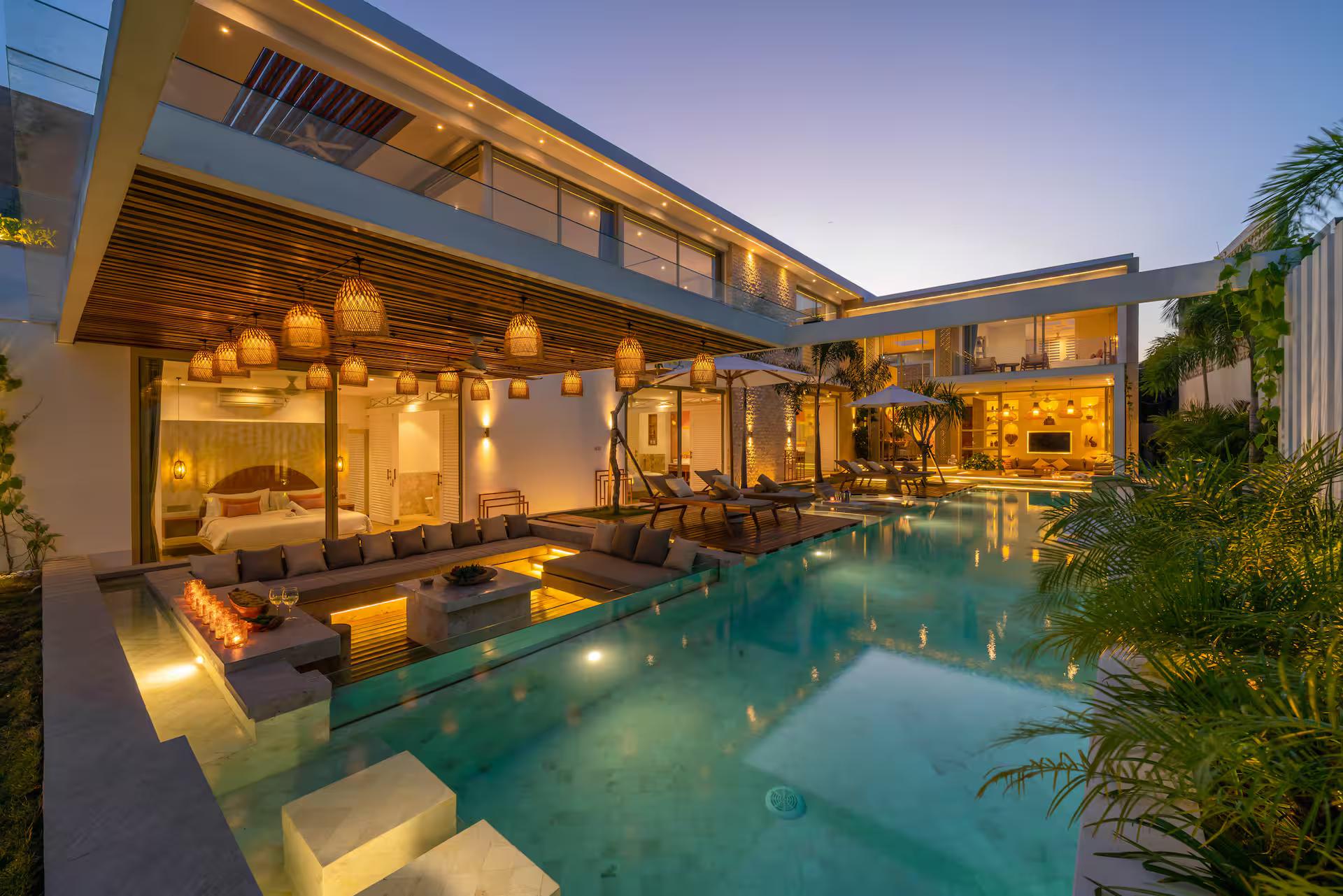 Villa Vida at dusk, the pool lit turquoise between the two glazed wings of the house