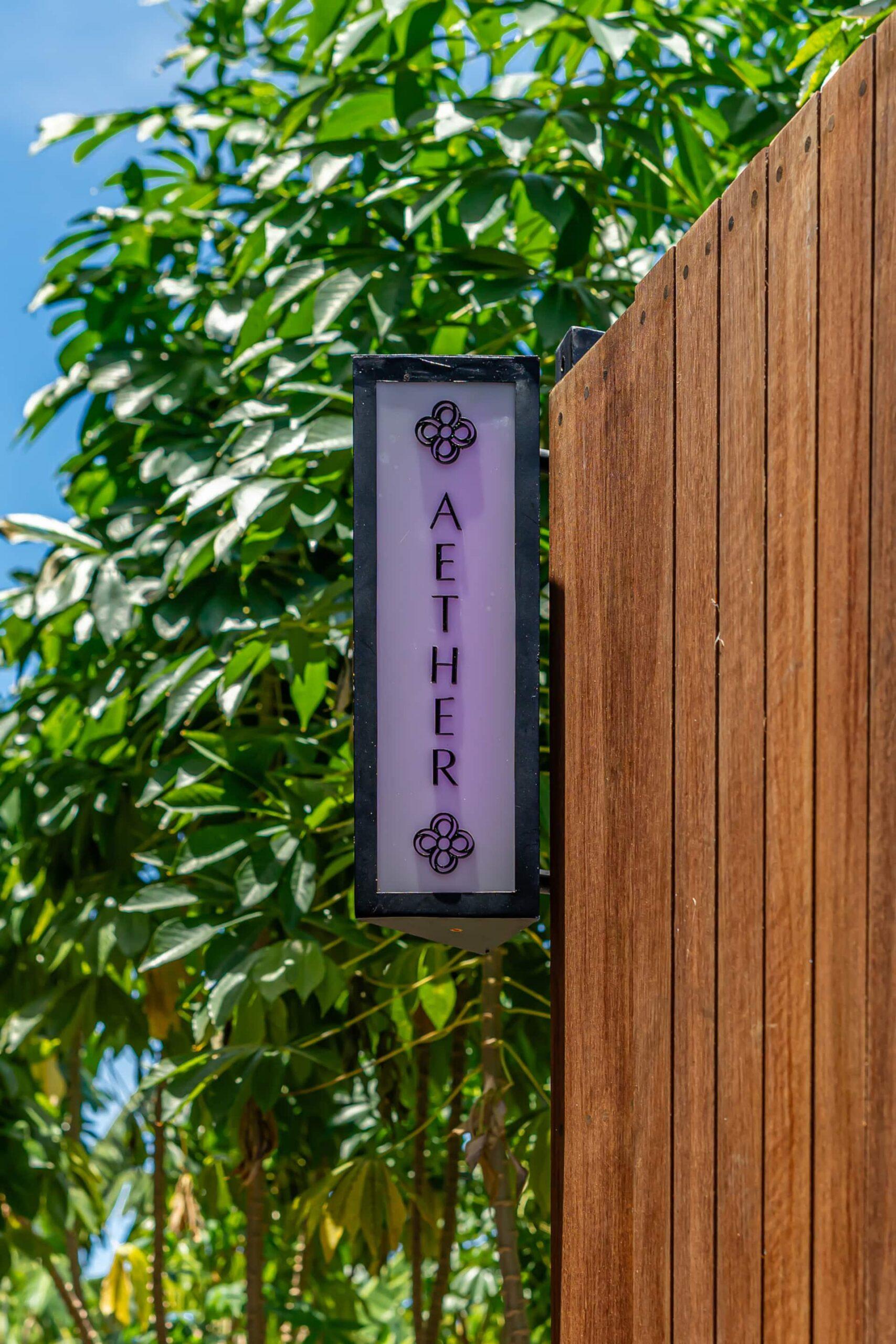 The villa's own timber gate carries a lit nameplate reading AETHER, the fifth Hidden Elements villa