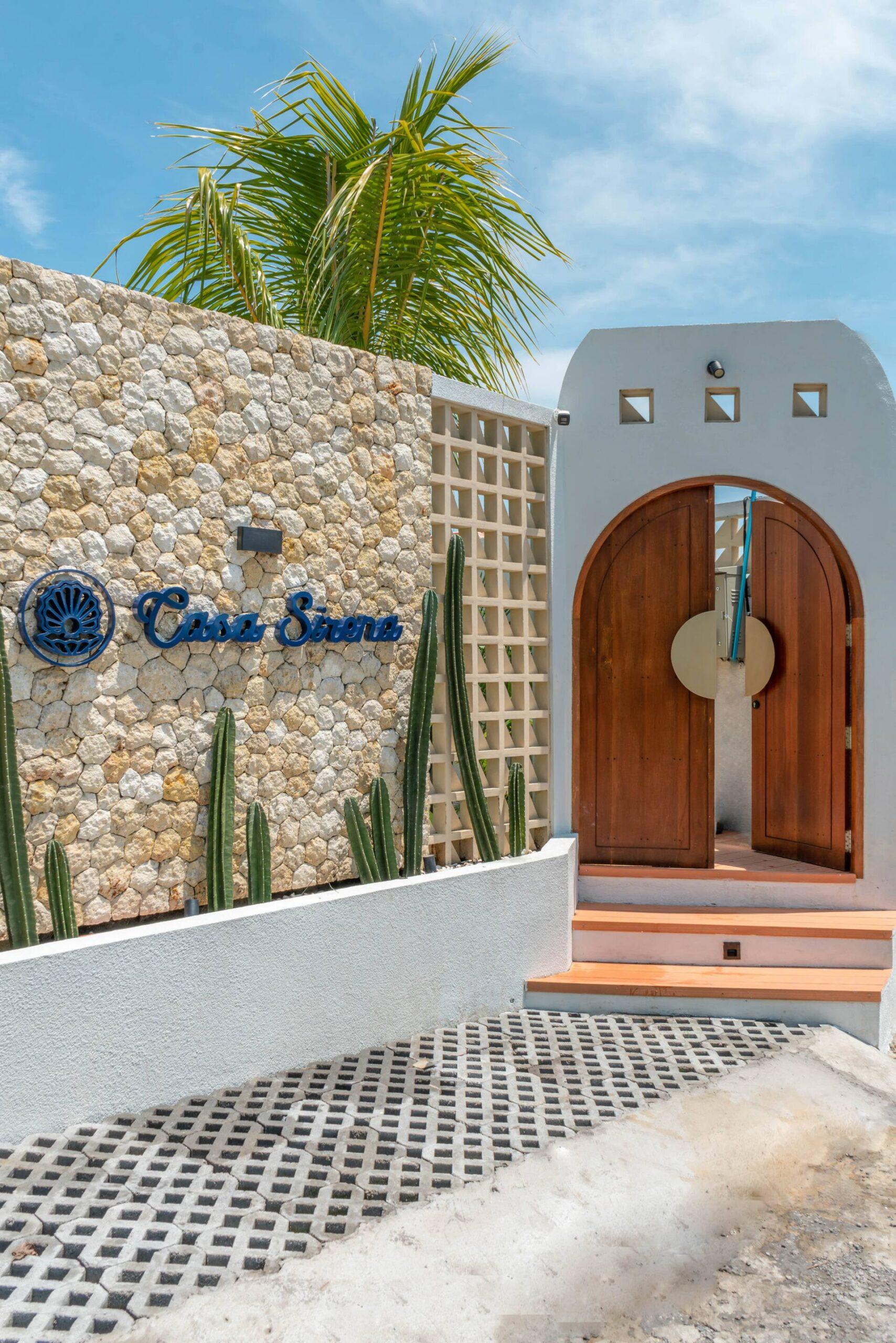 The villa's own nameplate — Casa Sirena in blue script — set on the coral-stone wall by the entrance gate