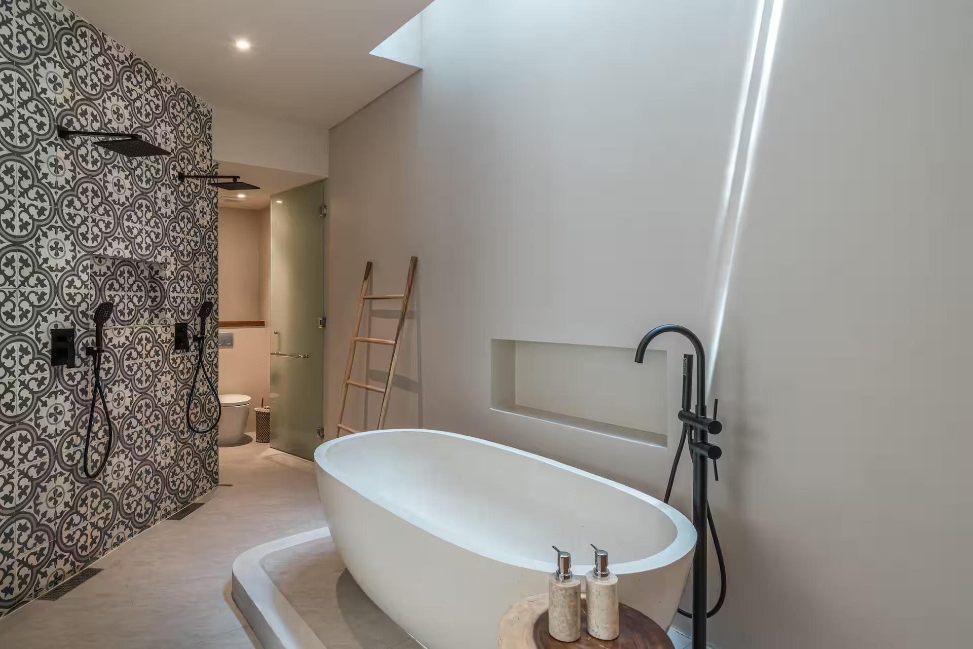 Freestanding oval tub beside a shower wall of monochrome patterned tile at Villa Yuko