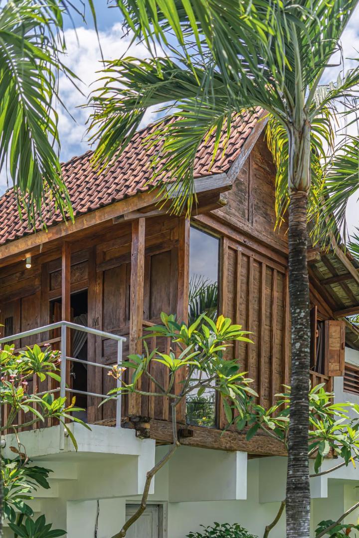 The teak loft house at Villa Palm Tree, red pantile roof and balcony among the palms