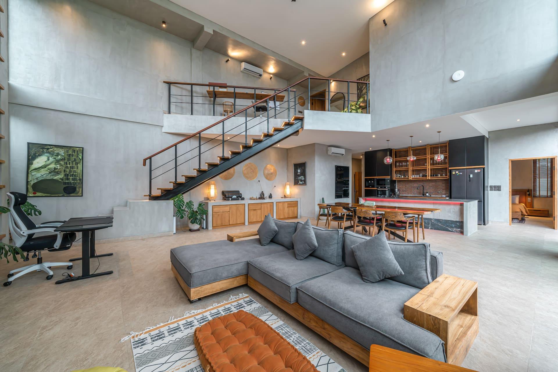 Loft living space with a steel-and-timber staircase rising to the mezzanine above the lounge