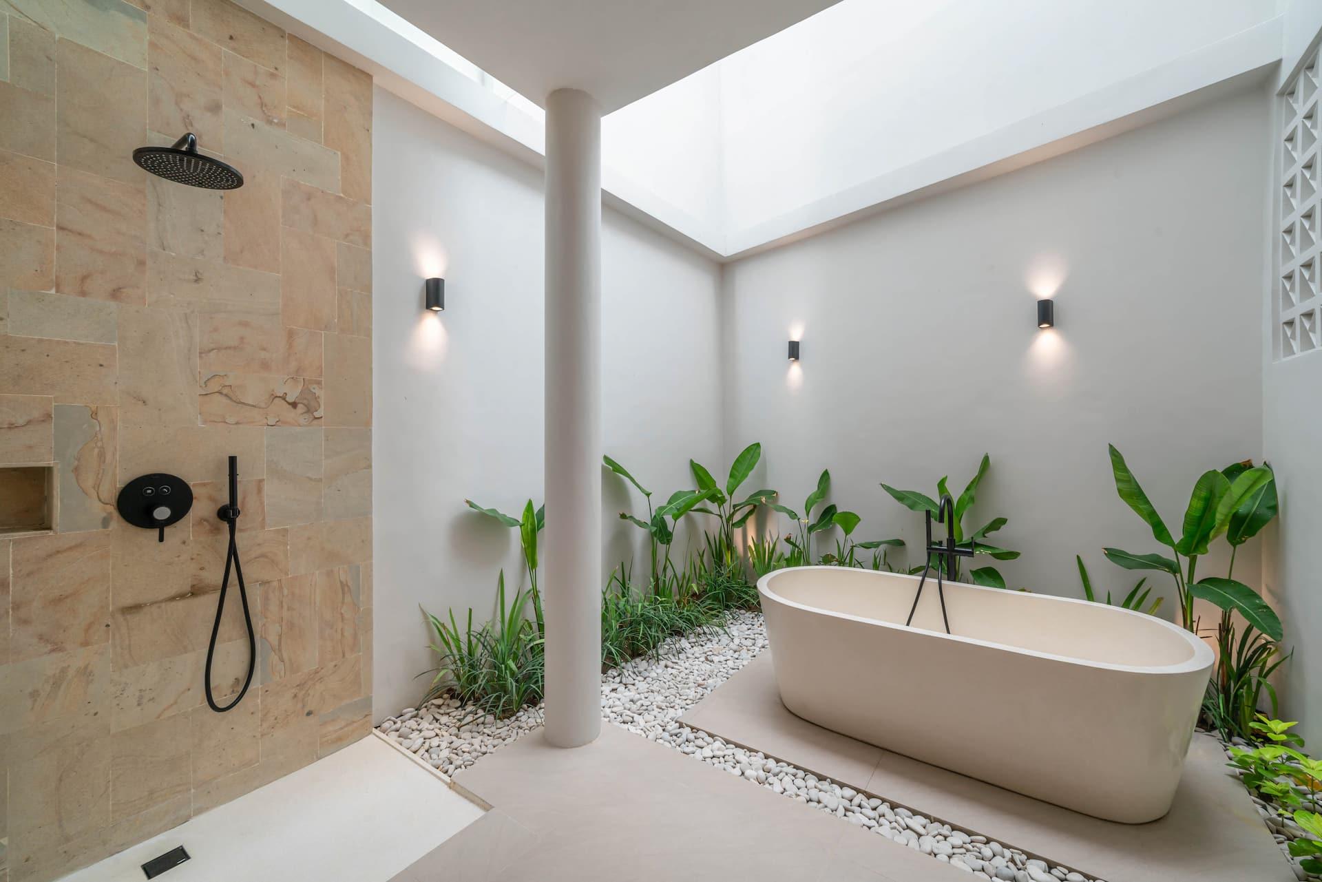 Freestanding outdoor bathtub in a pebble courtyard at Villa LouLou, framed by tropical planting