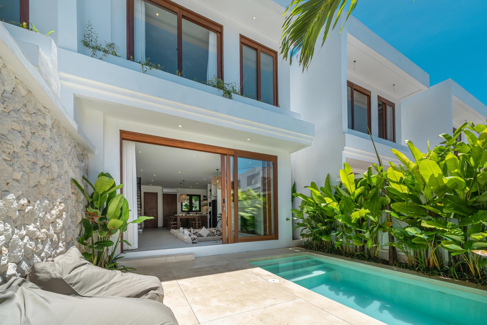 Looking out from the cushioned bench across the pool to the timber-framed glass doors