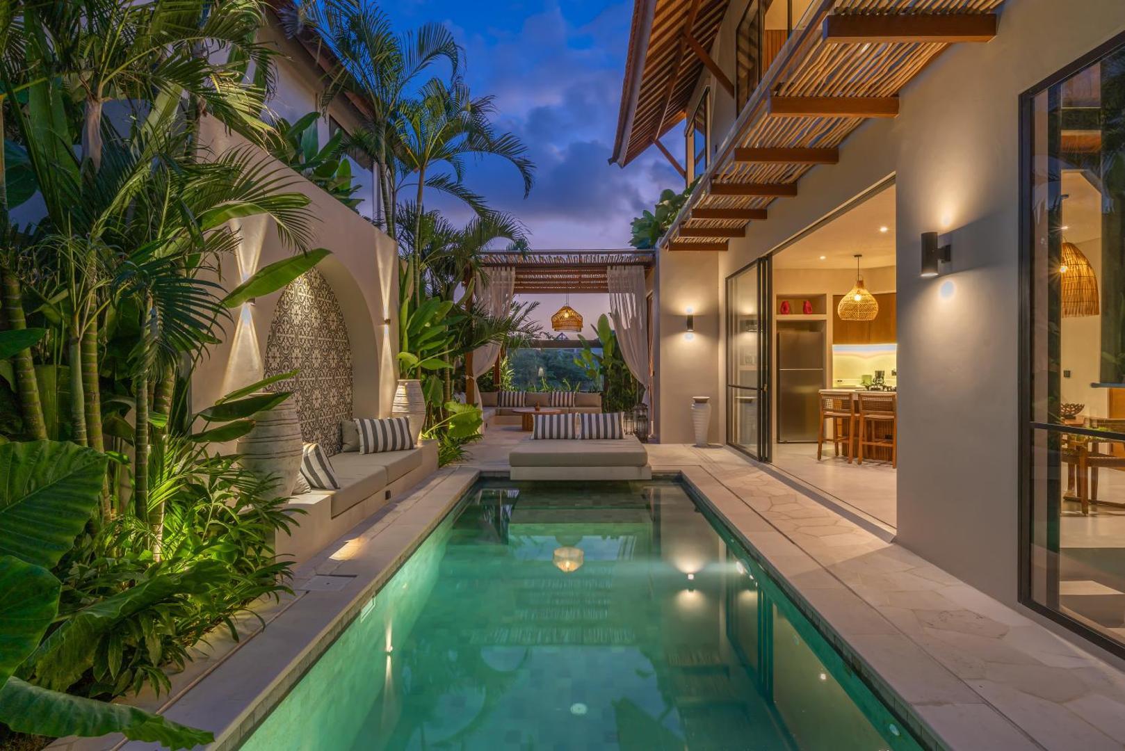 Villa Nalaka at dusk, the lit pool running between planting and the open living room