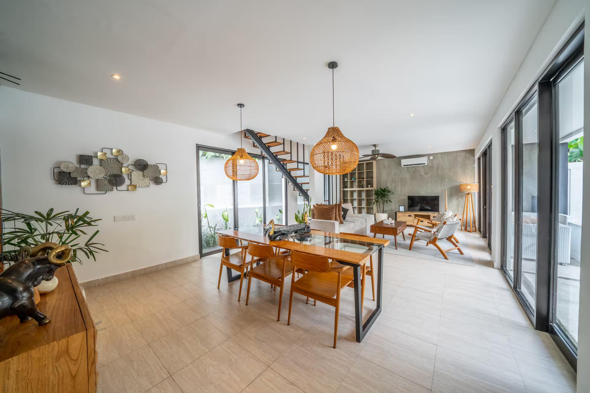 Dining table for six under woven rattan pendants beside the stair at Villa Anna